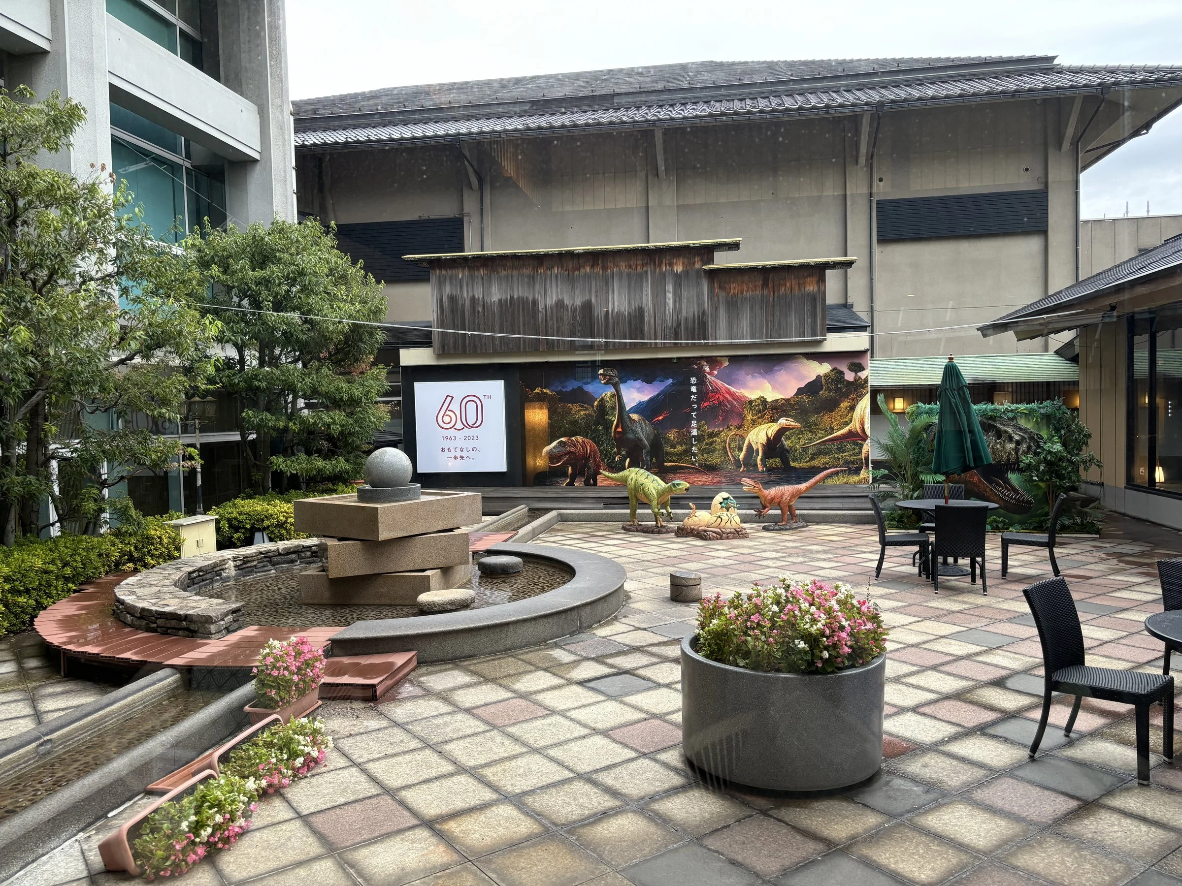 The courtyard photo spot, with dinosaur figures and a fountain, on a rainy afternoon.