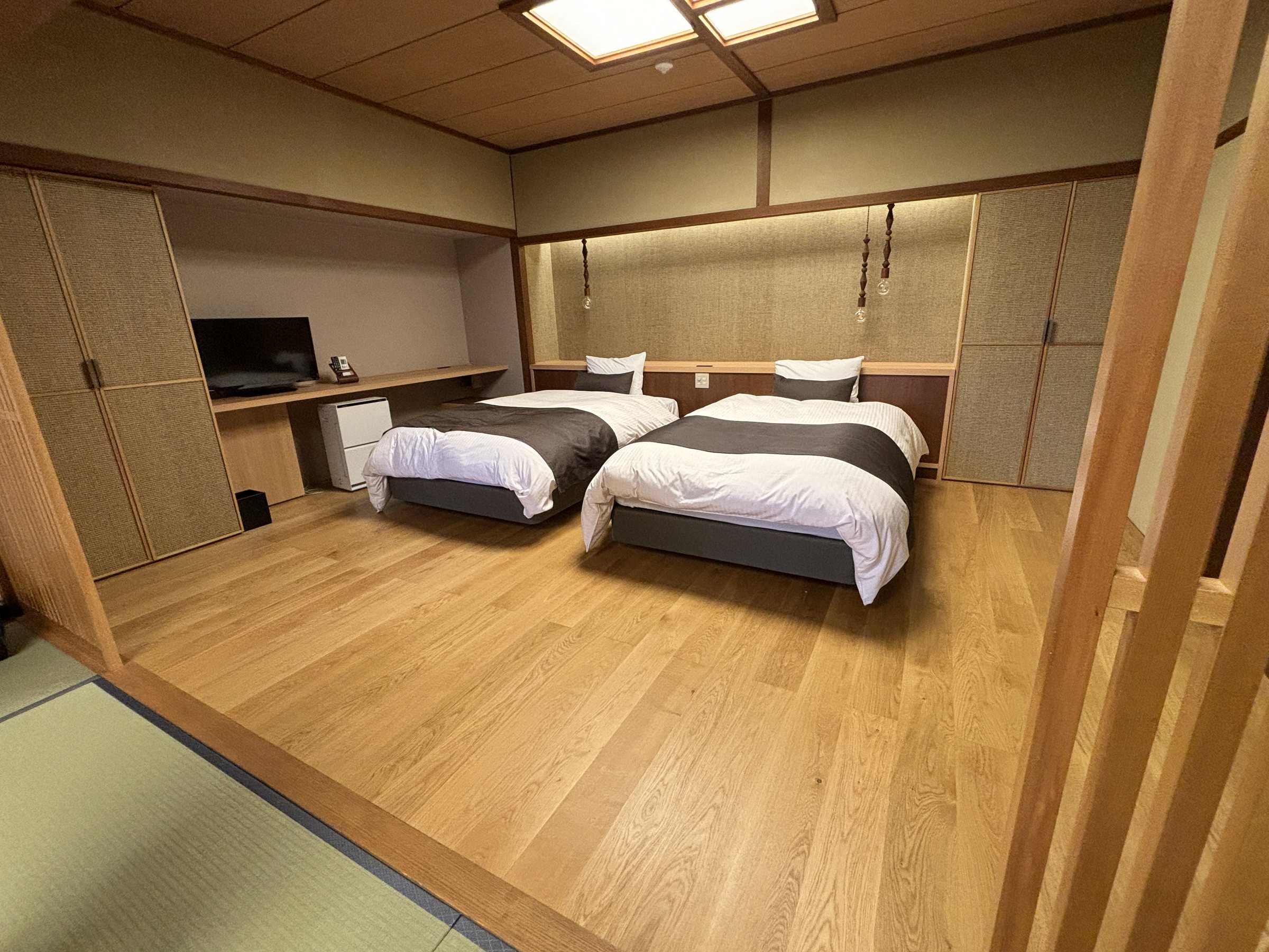 Twin beds on a wooden floor beside the tatami area.