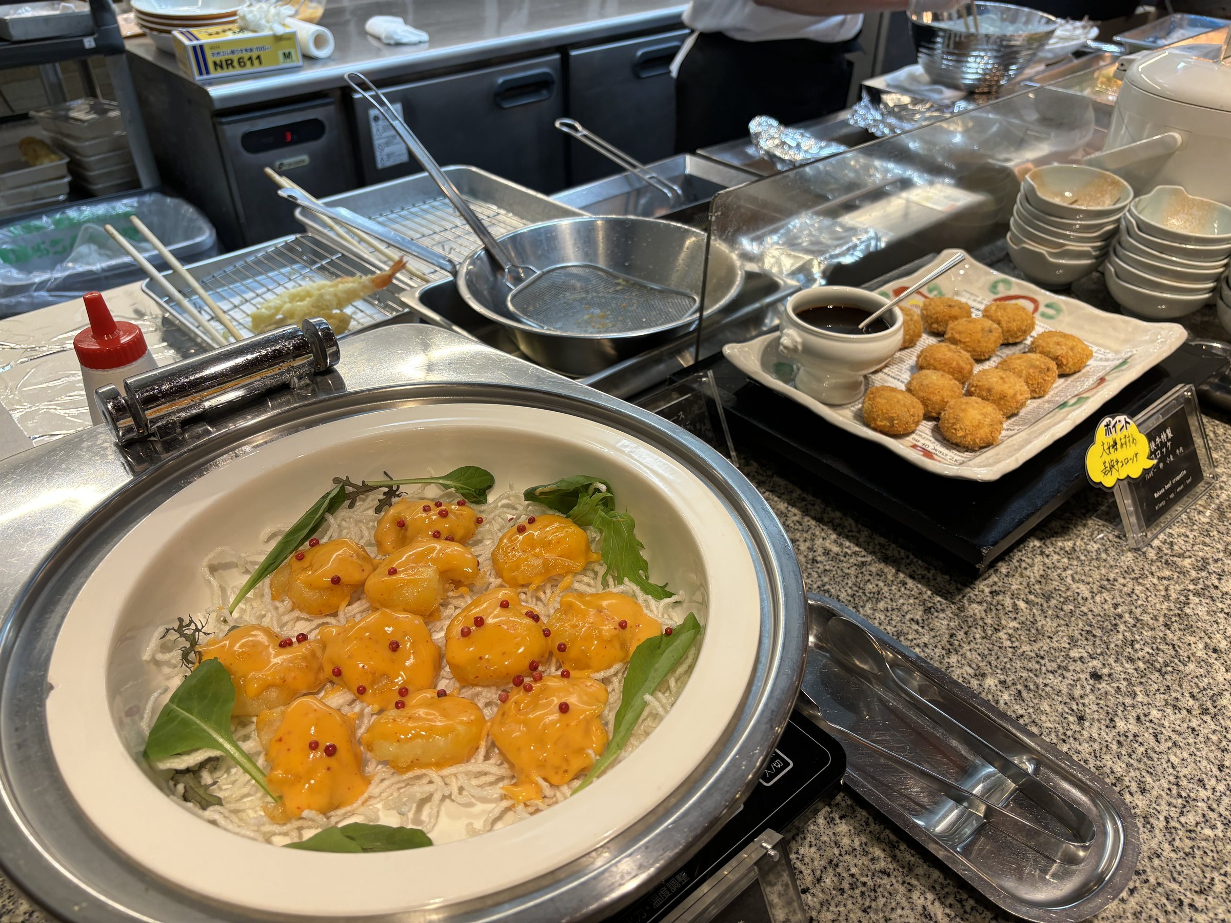 Prawns in a bright orange sauce at a hot station.
