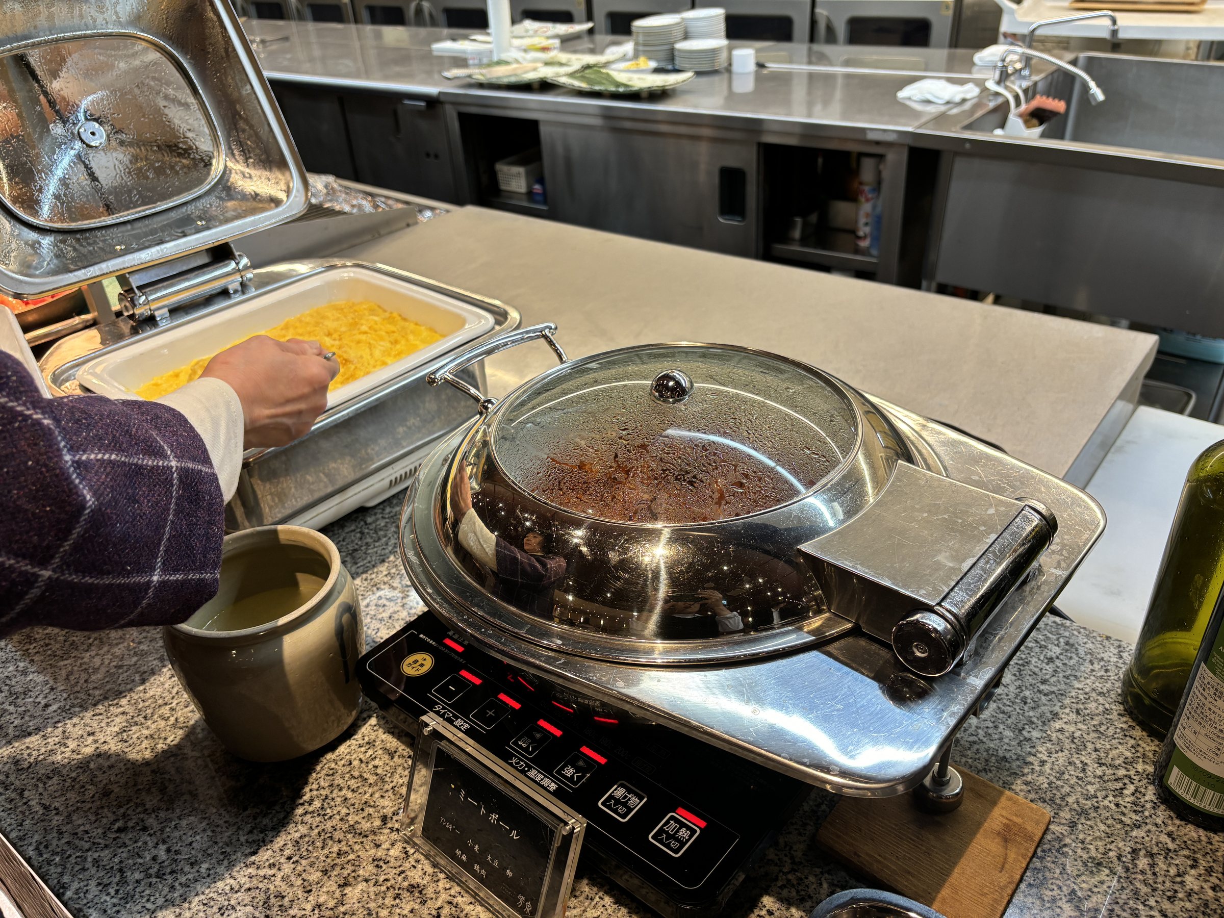 Scrambled eggs and a covered pan on a hotplate.