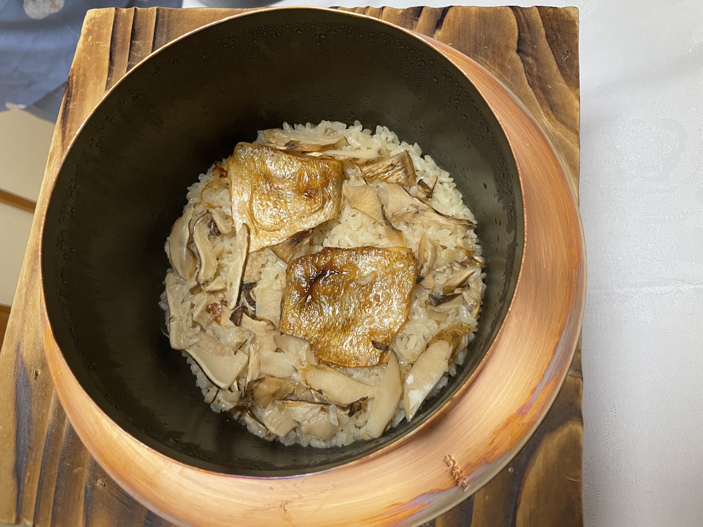 Autumn rice cooked with matsutake and fish in a small pot.