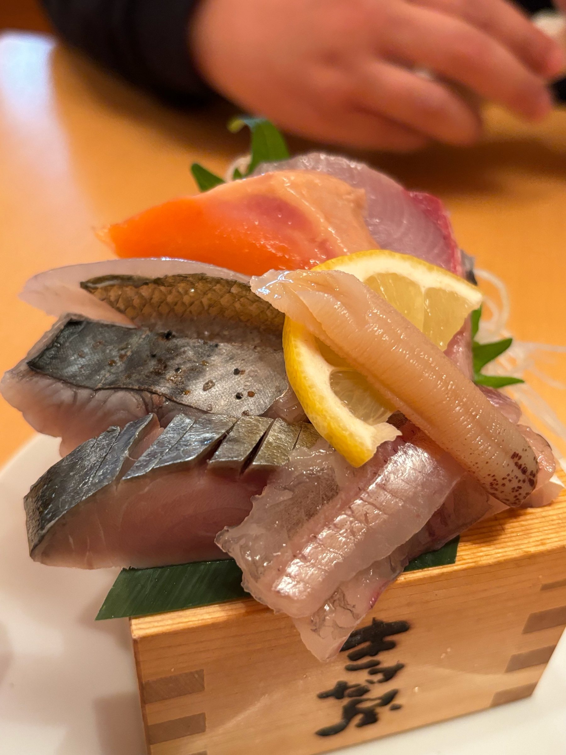 Sashimi heaped on a wooden masu box.