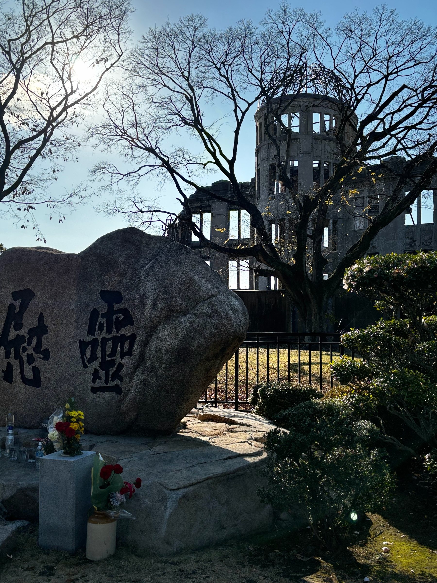 The Atomic Bomb Dome behind a memorial stone, flowers laid in front.