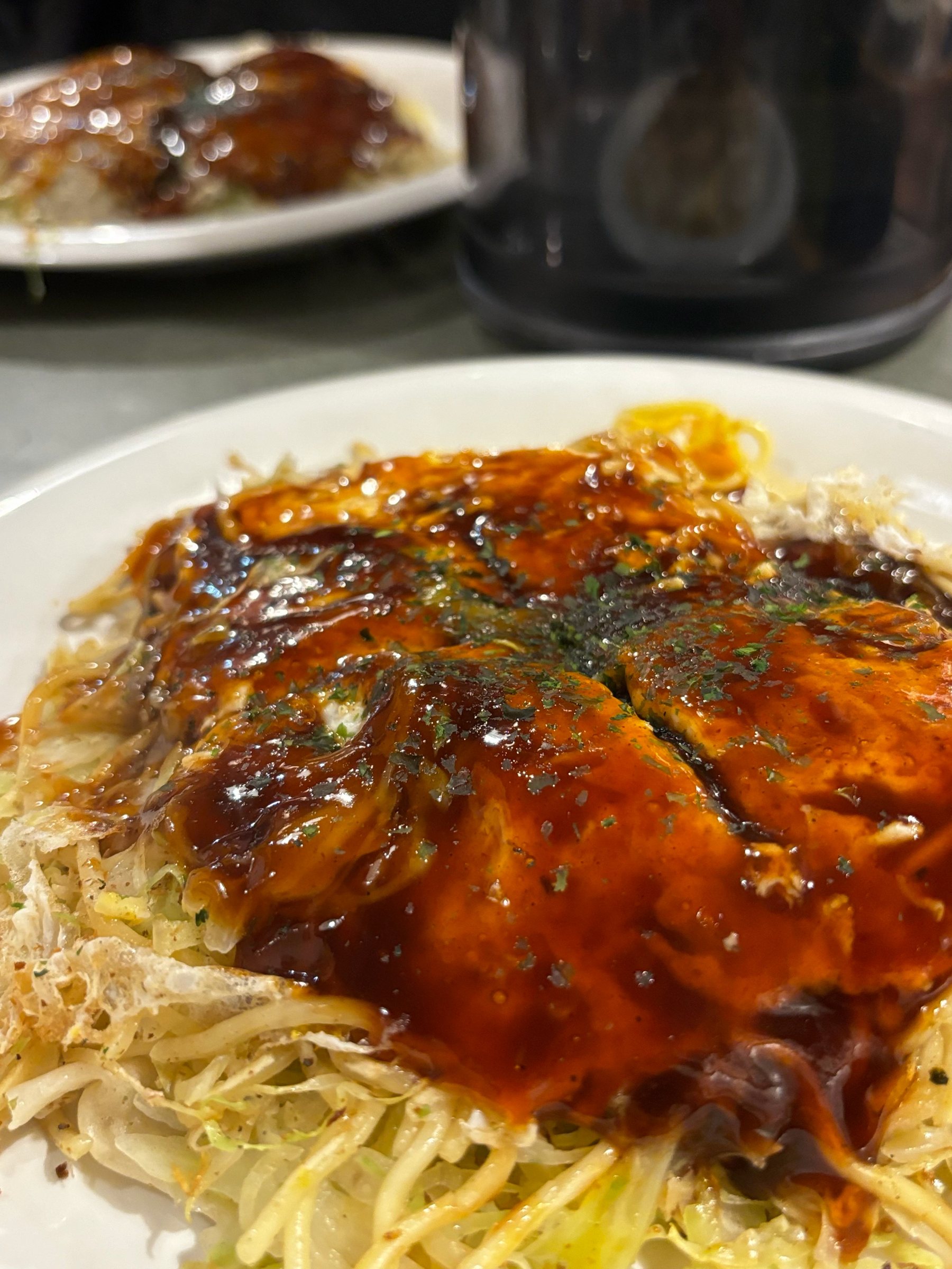 Hiroshima-style okonomiyaki, glossy with sauce and sprinkled with aonori.