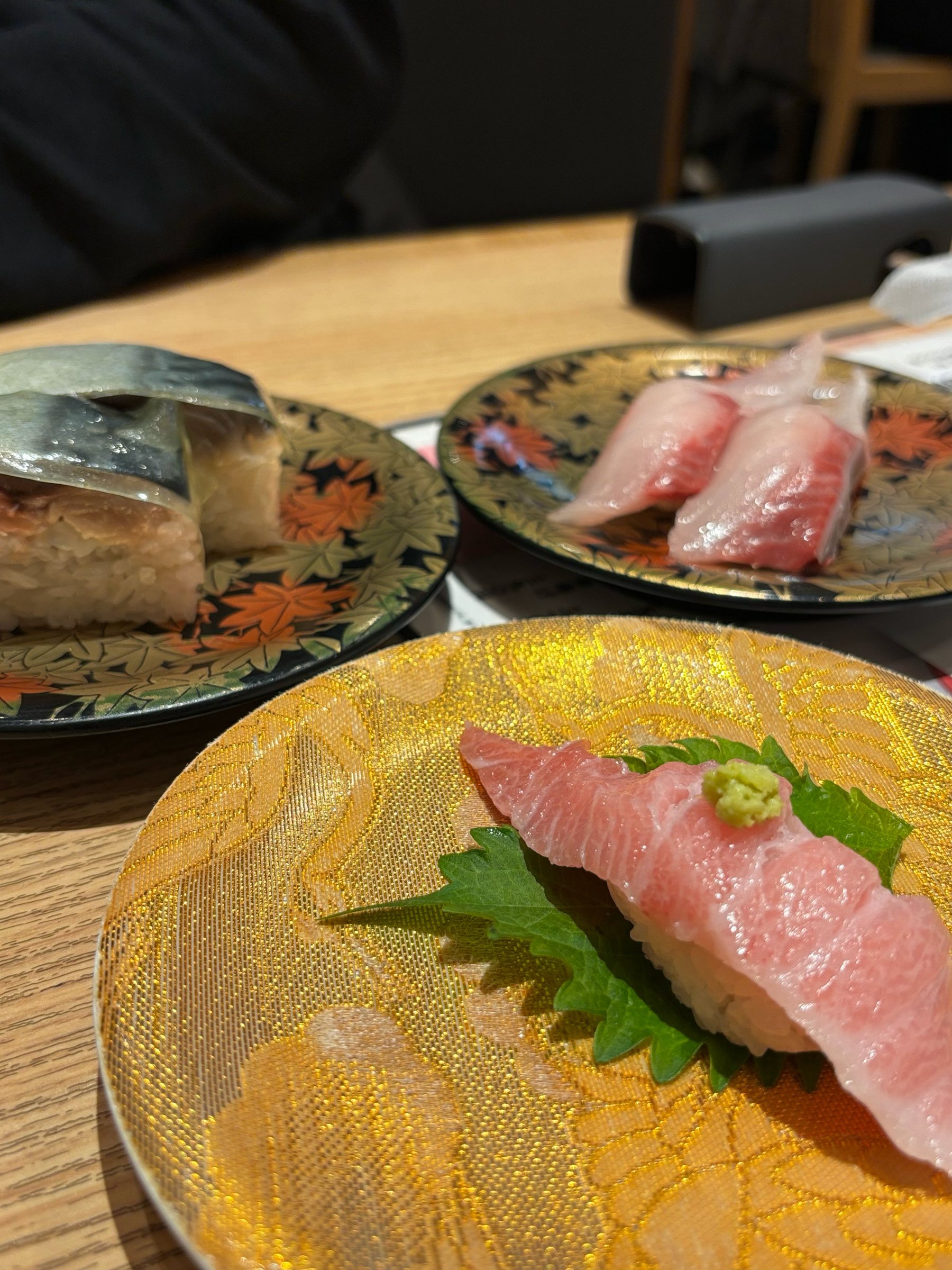 Otoro, shime saba and white fish on gold-patterned plates.