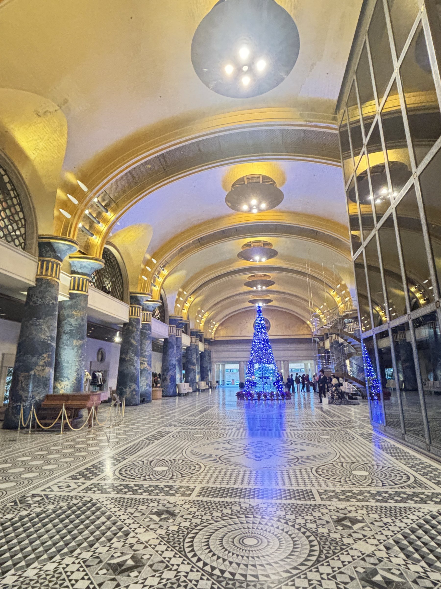 The long gallery, with a blue-lit Christmas tree beneath the gilded vault.