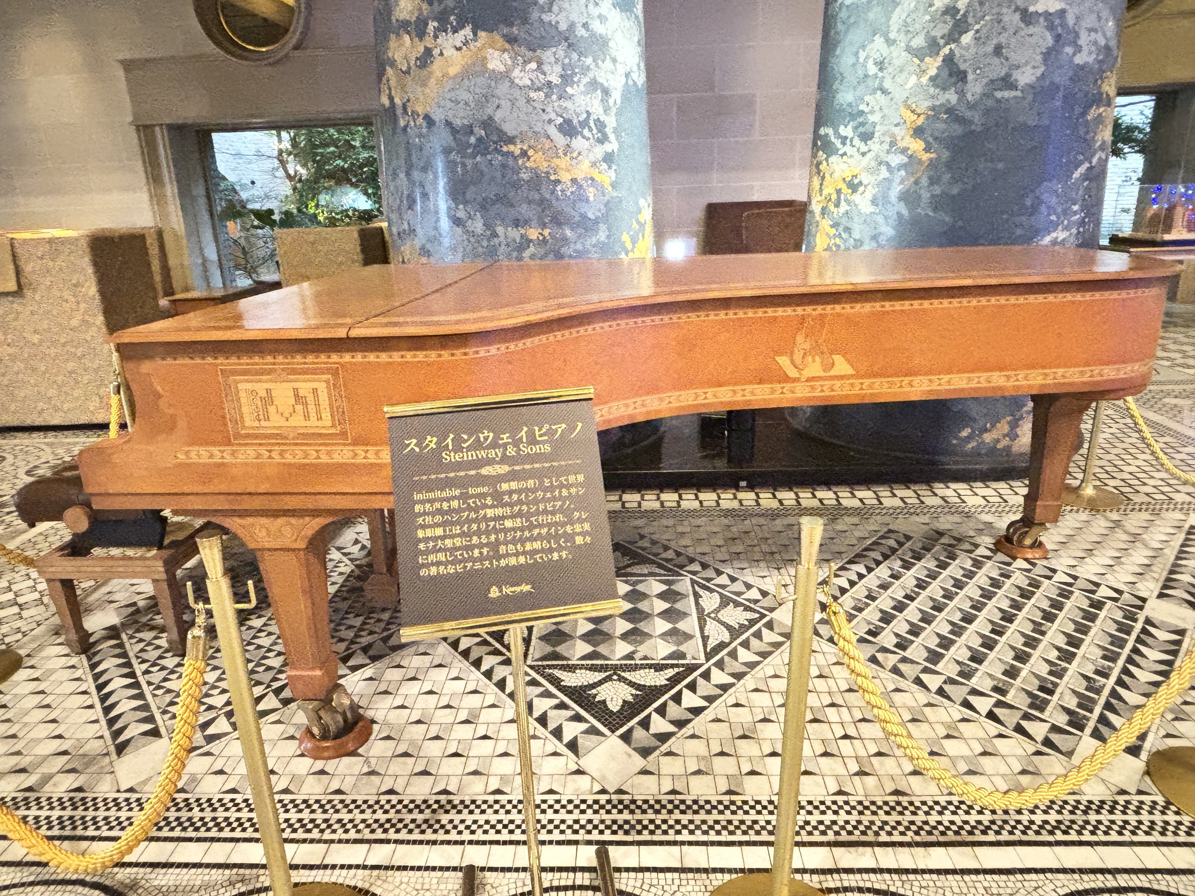 The bespoke inlaid Steinway, roped off before blue columns.