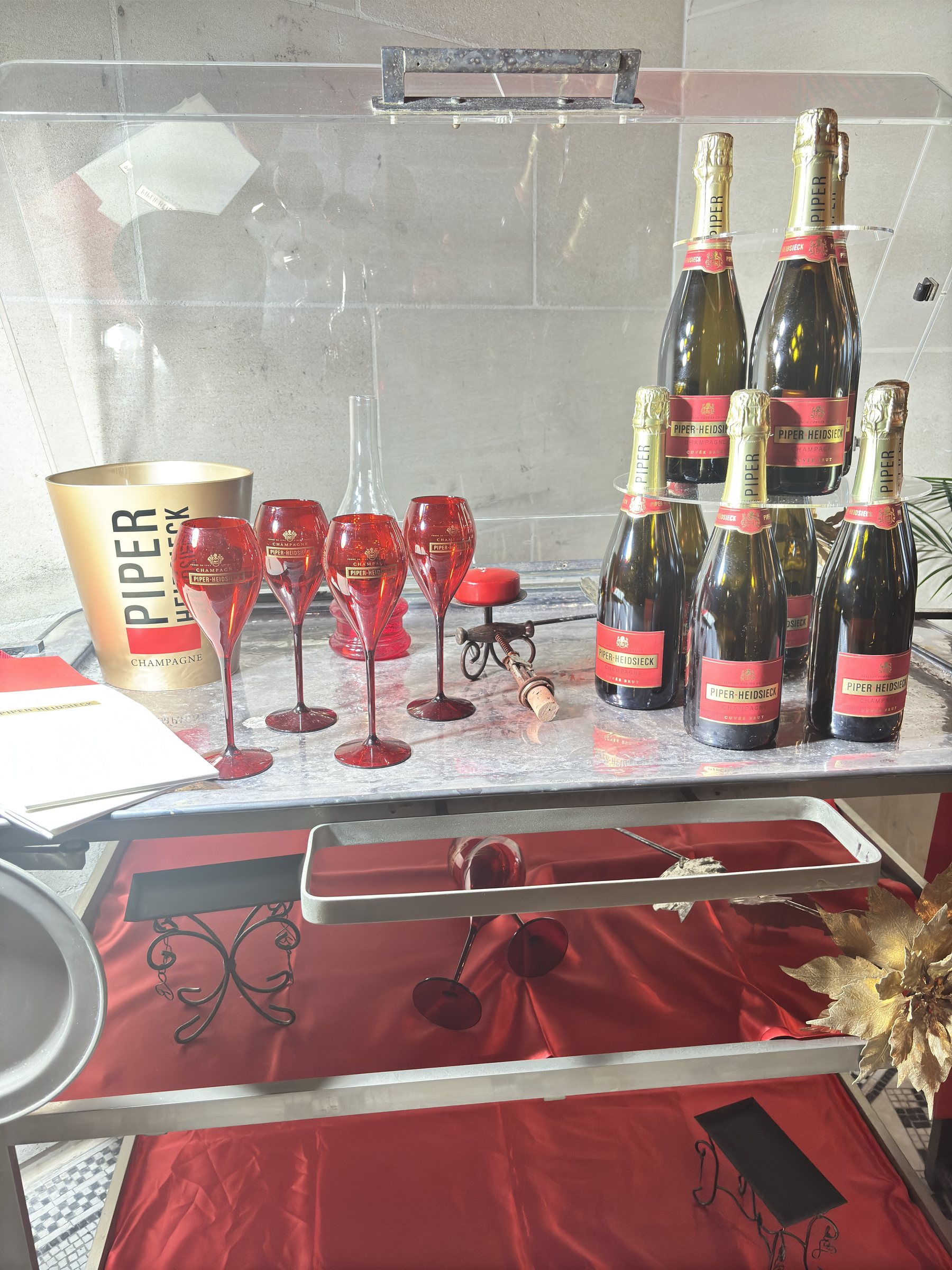 Piper-Heidsieck bottles and red flutes on a champagne trolley.