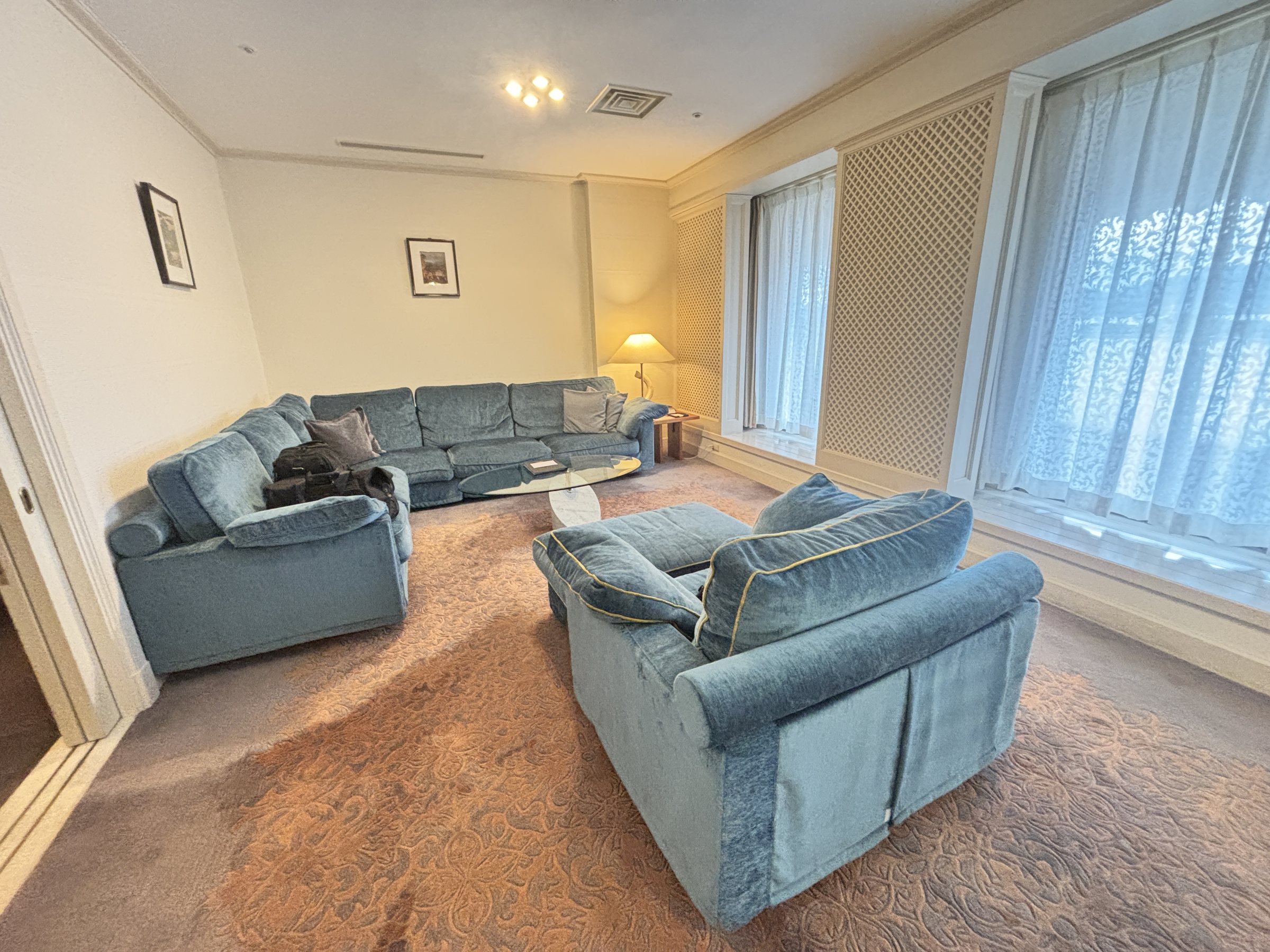 The living area, with large blue sofas and tall windows.