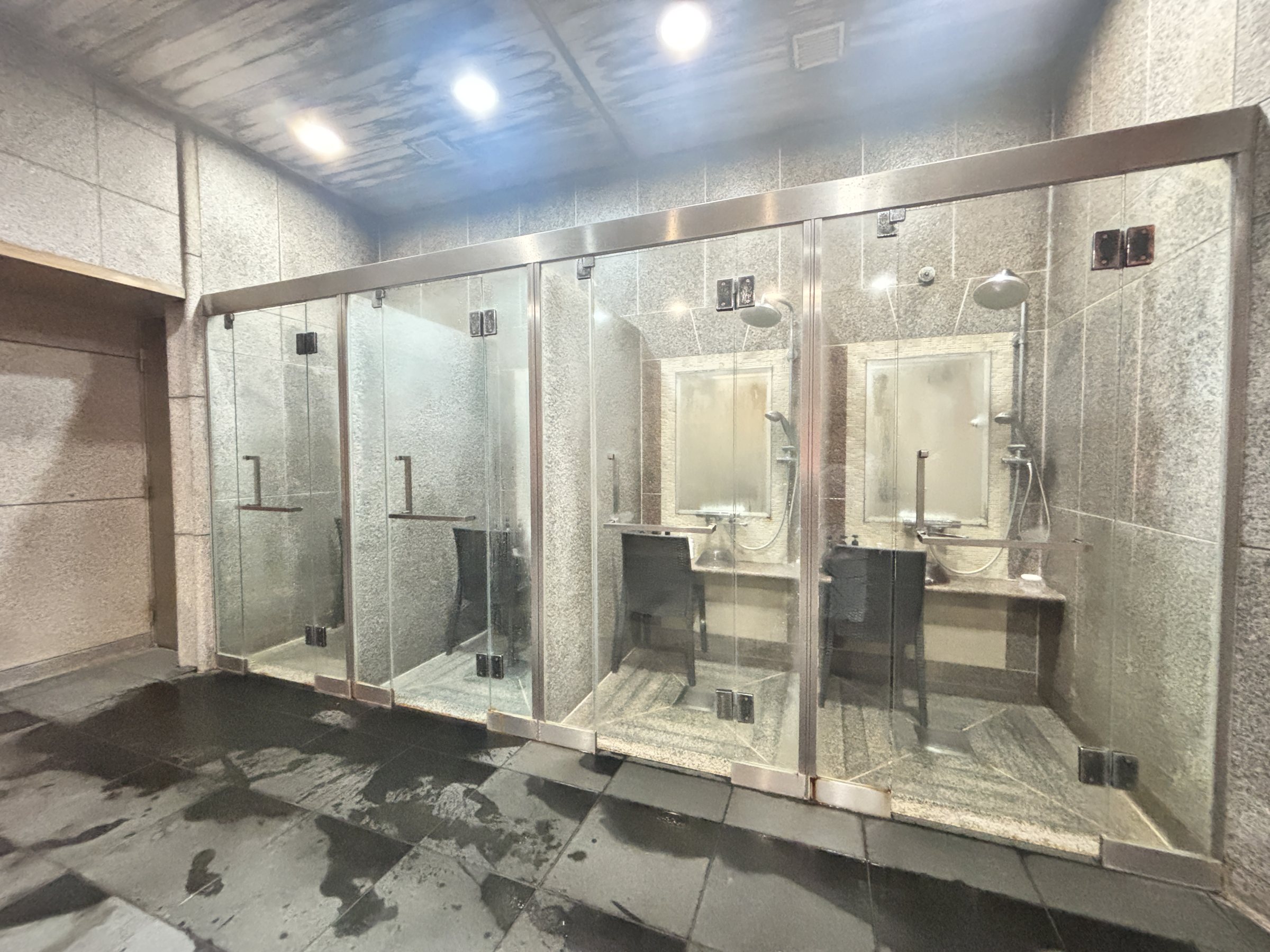 Glass-walled shower booths in the stone-clad bathing area.