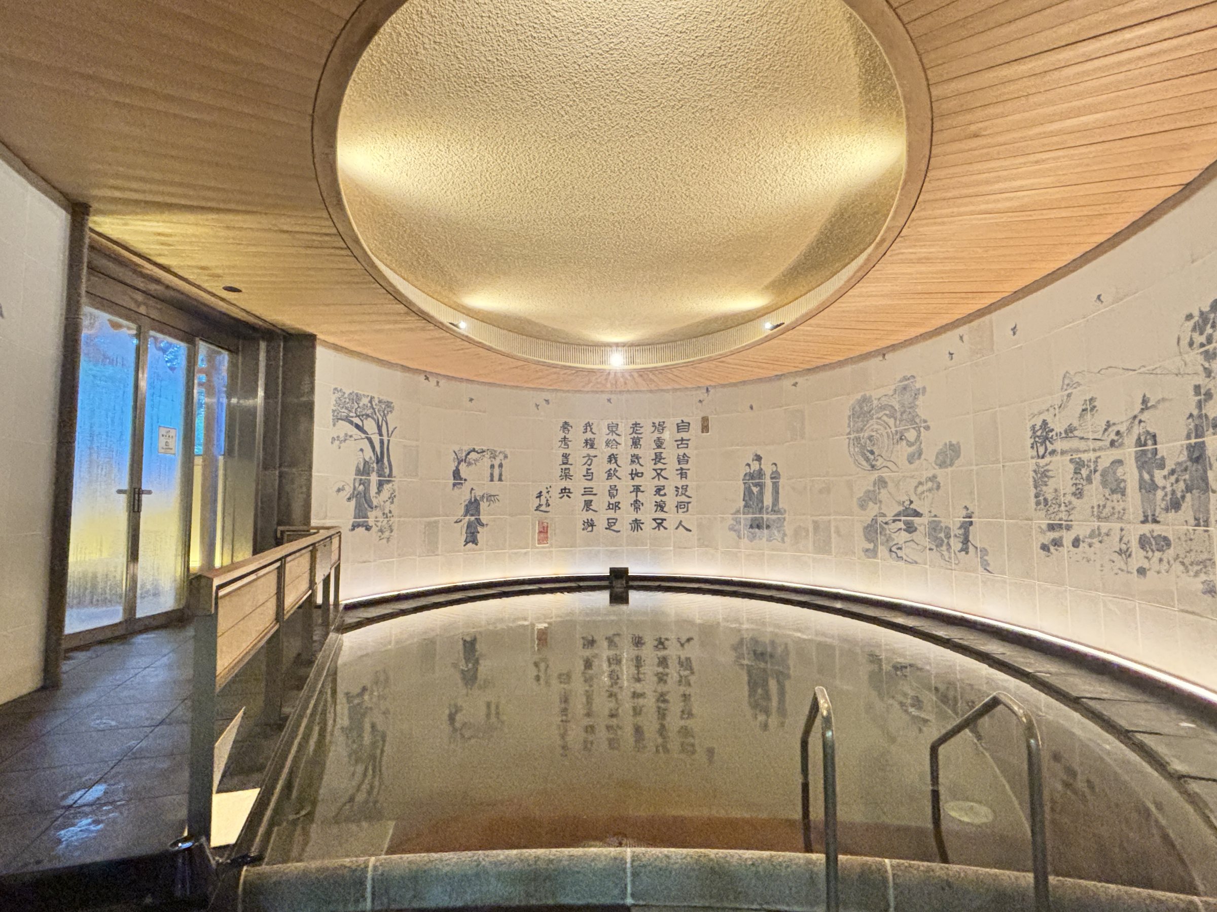 The circular indoor bath beneath a domed ceiling, with painted tiles around the walls.