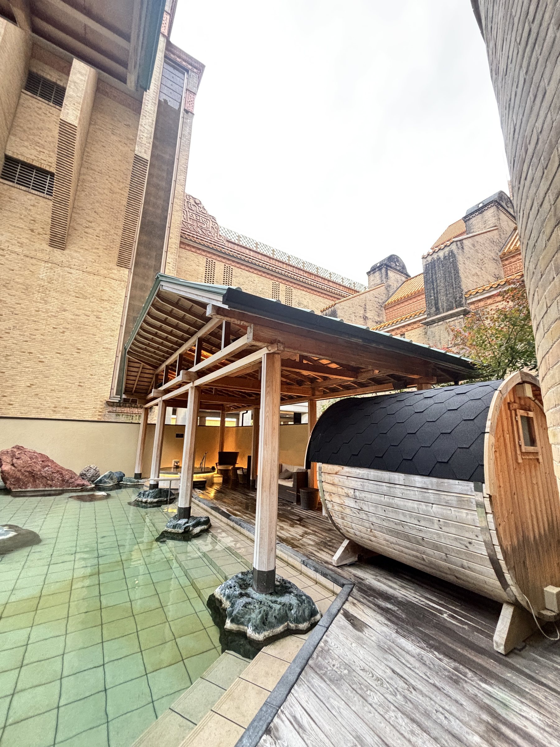 The open-air bath and barrel sauna beneath the hotel's high walls.
