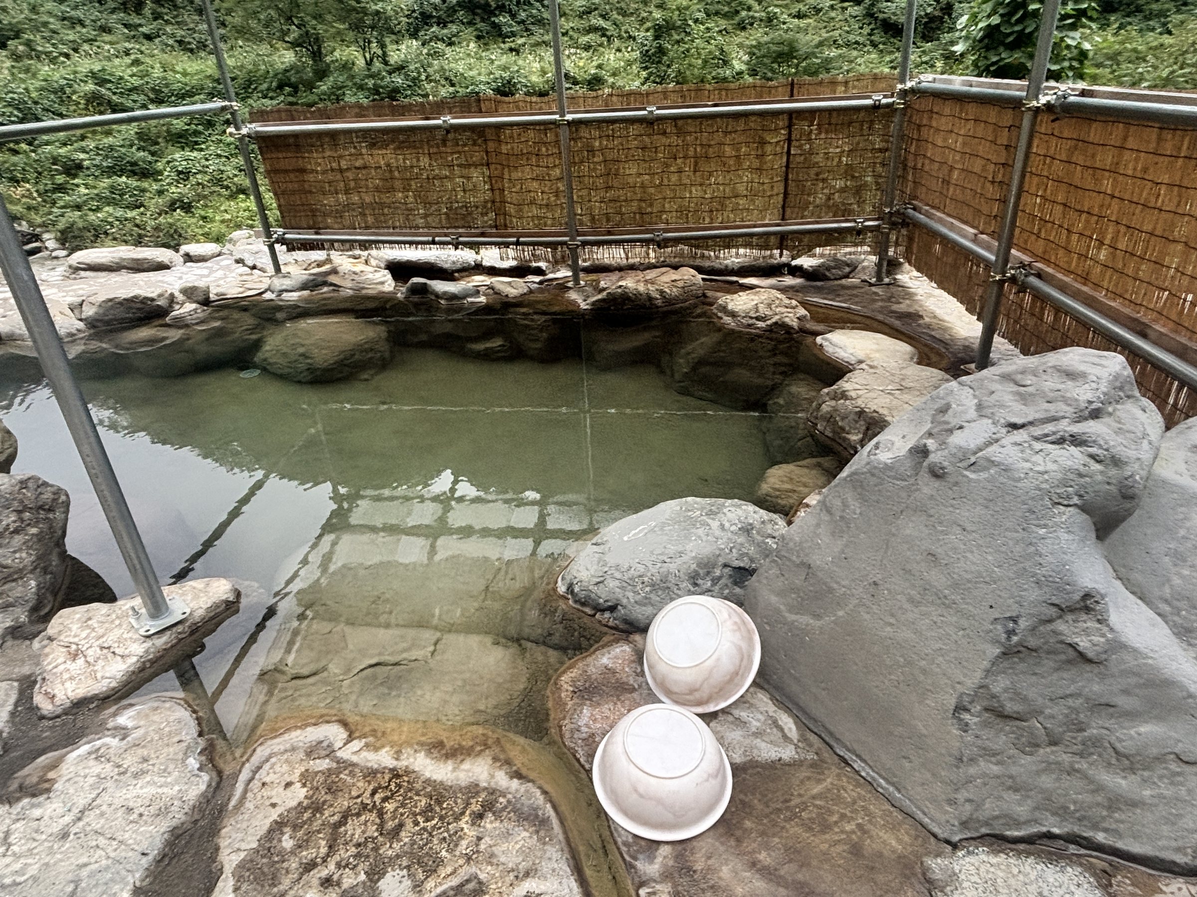 The rock-lined outdoor bath, screened by bamboo fencing.