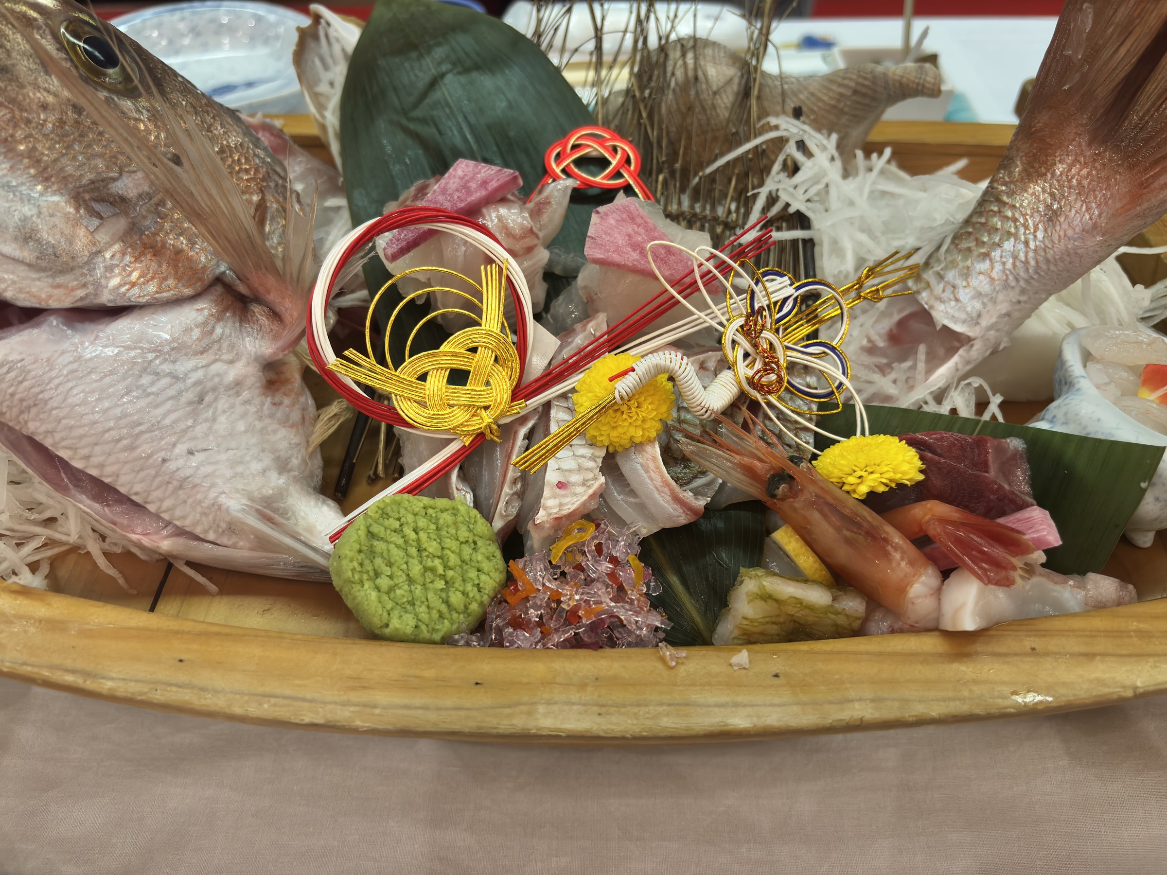 The sashimi boat, garnished with whole fish and a decorative knot.
