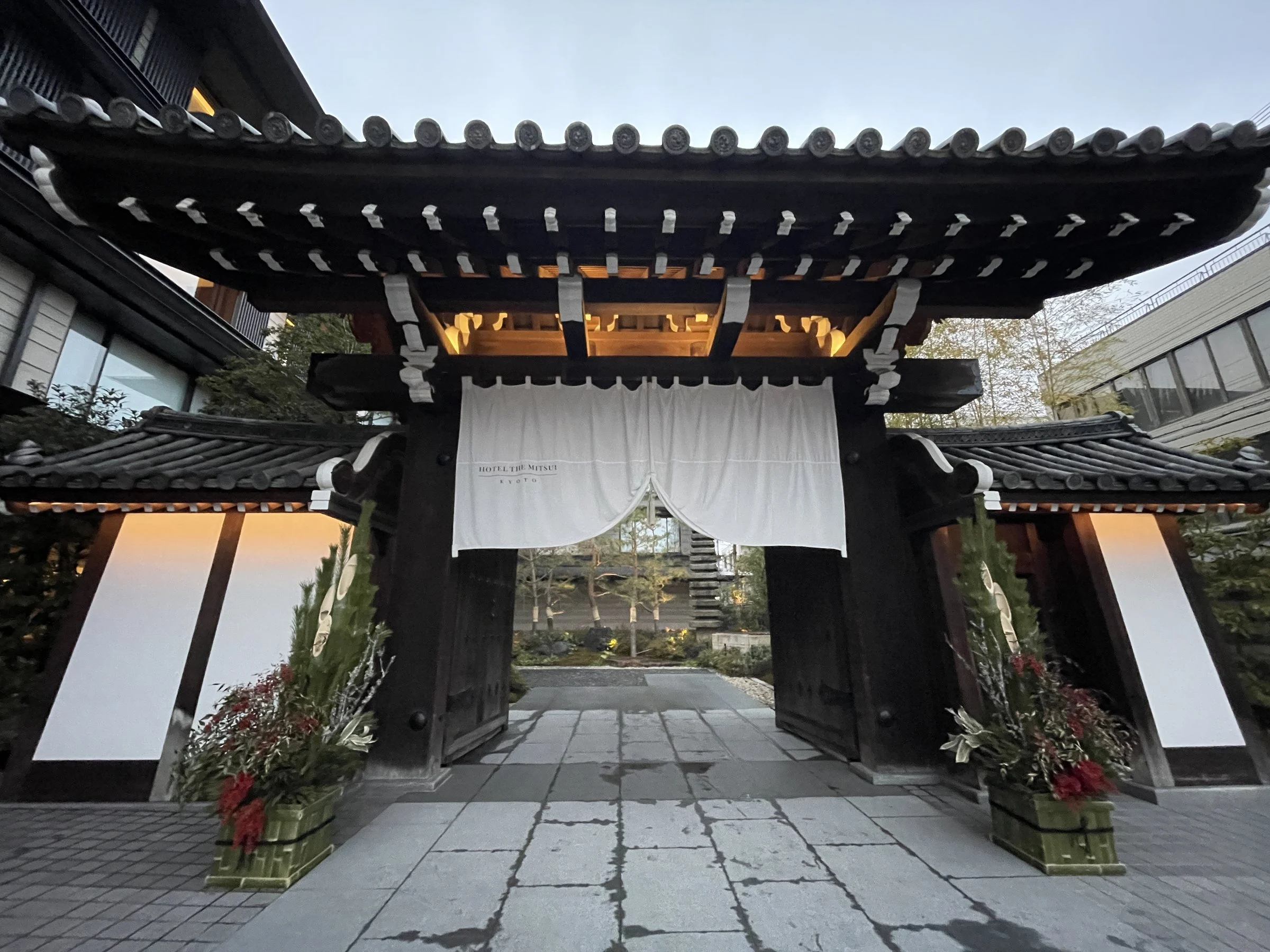 The hotel's gate: a heavy tiled roof, white noren curtains and decorative pine arrangements on either side.