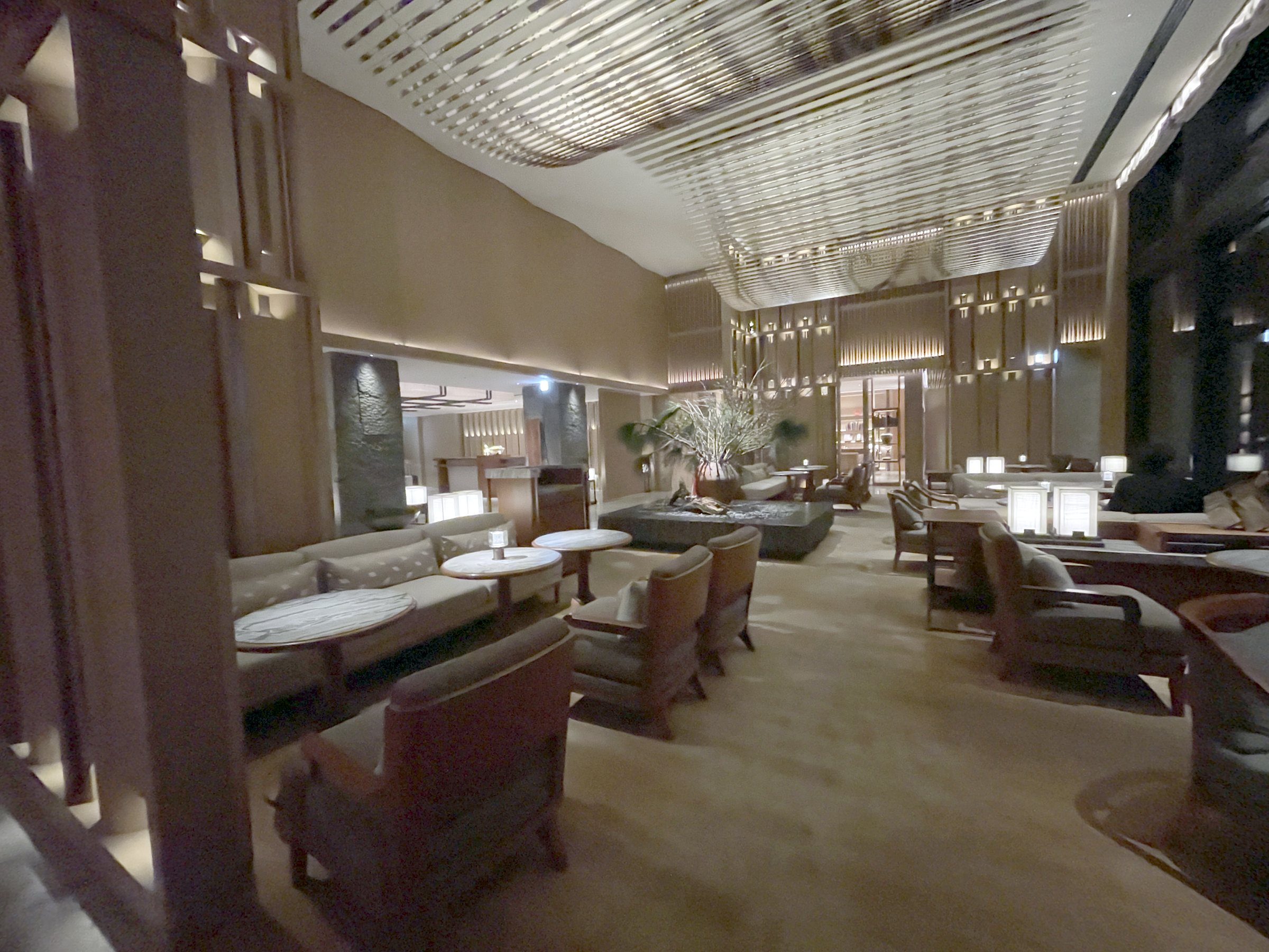 The lobby lounge in low, warm lighting beneath a ribbed ceiling.