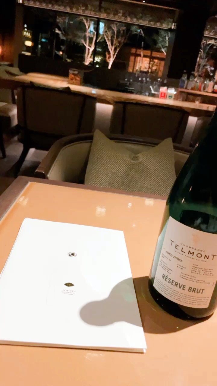 A bottle of sparkling wine on our table, with the bar softly lit behind.