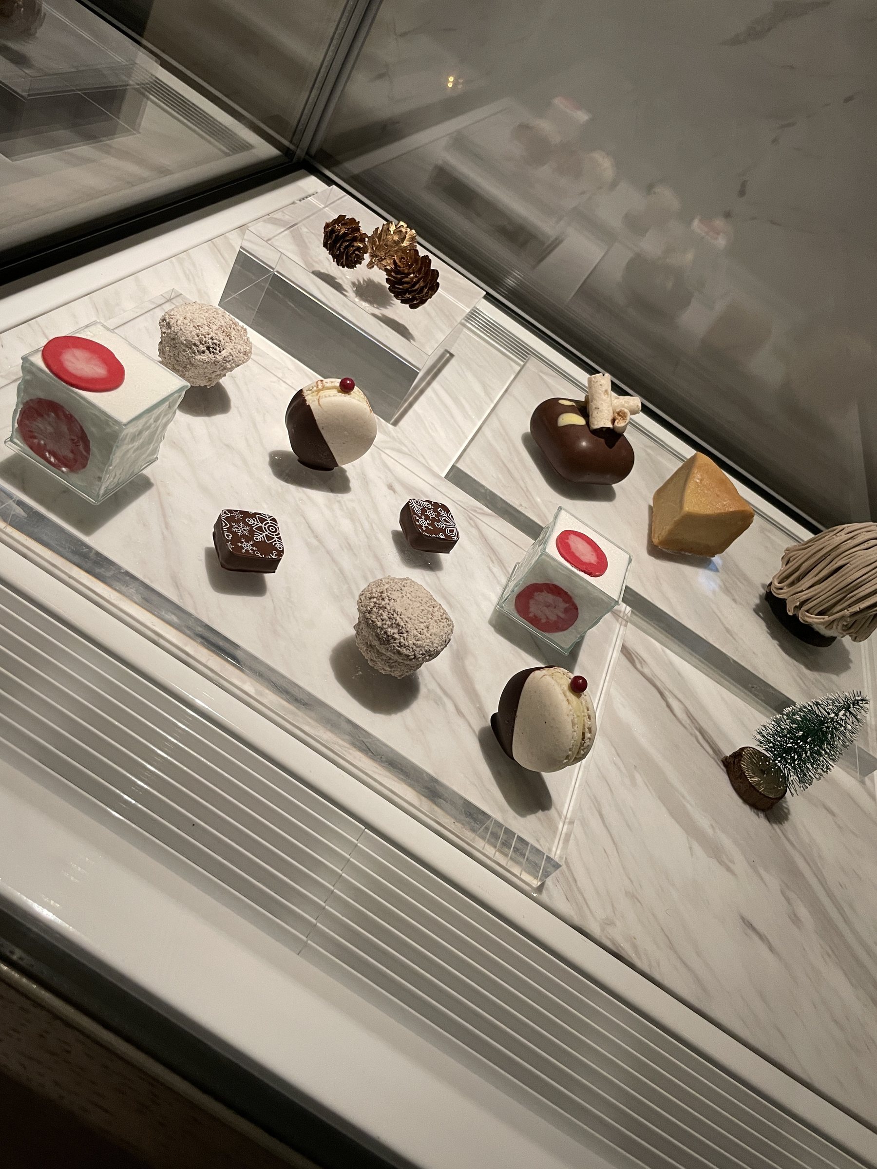 Small cakes and chocolates displayed in a glass case.