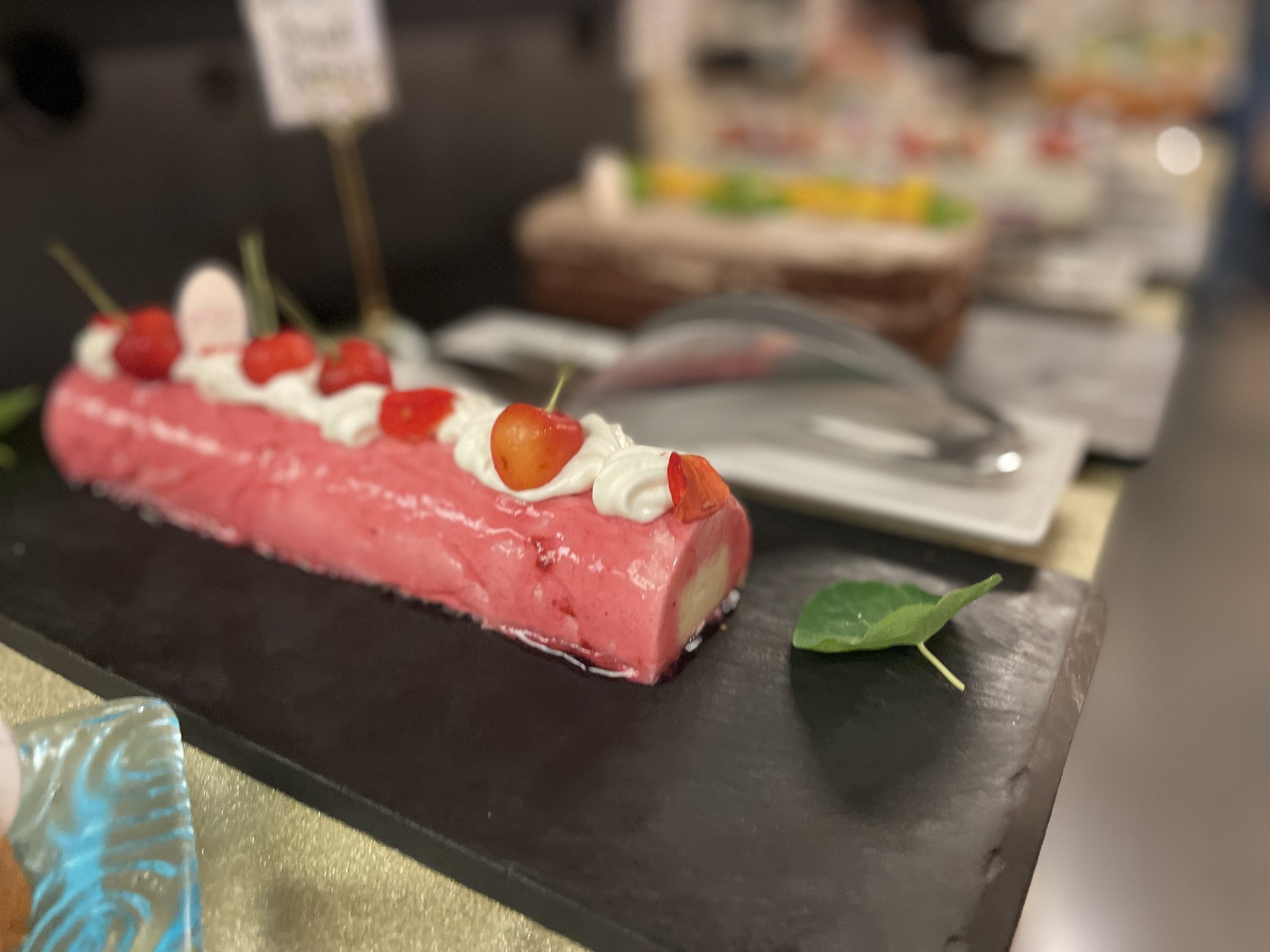 A pink roll cake decorated with strawberries and cream.