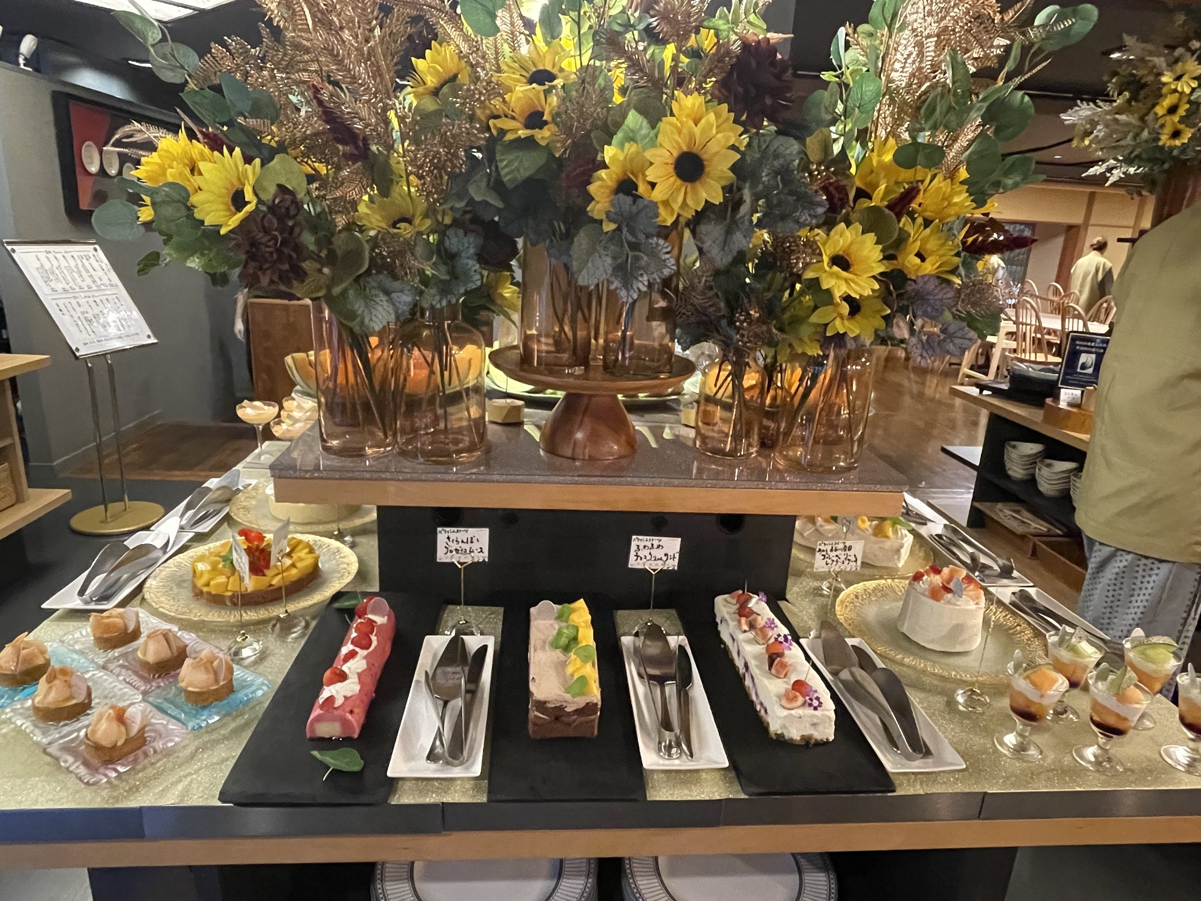 The dessert table beneath a large arrangement of sunflowers.