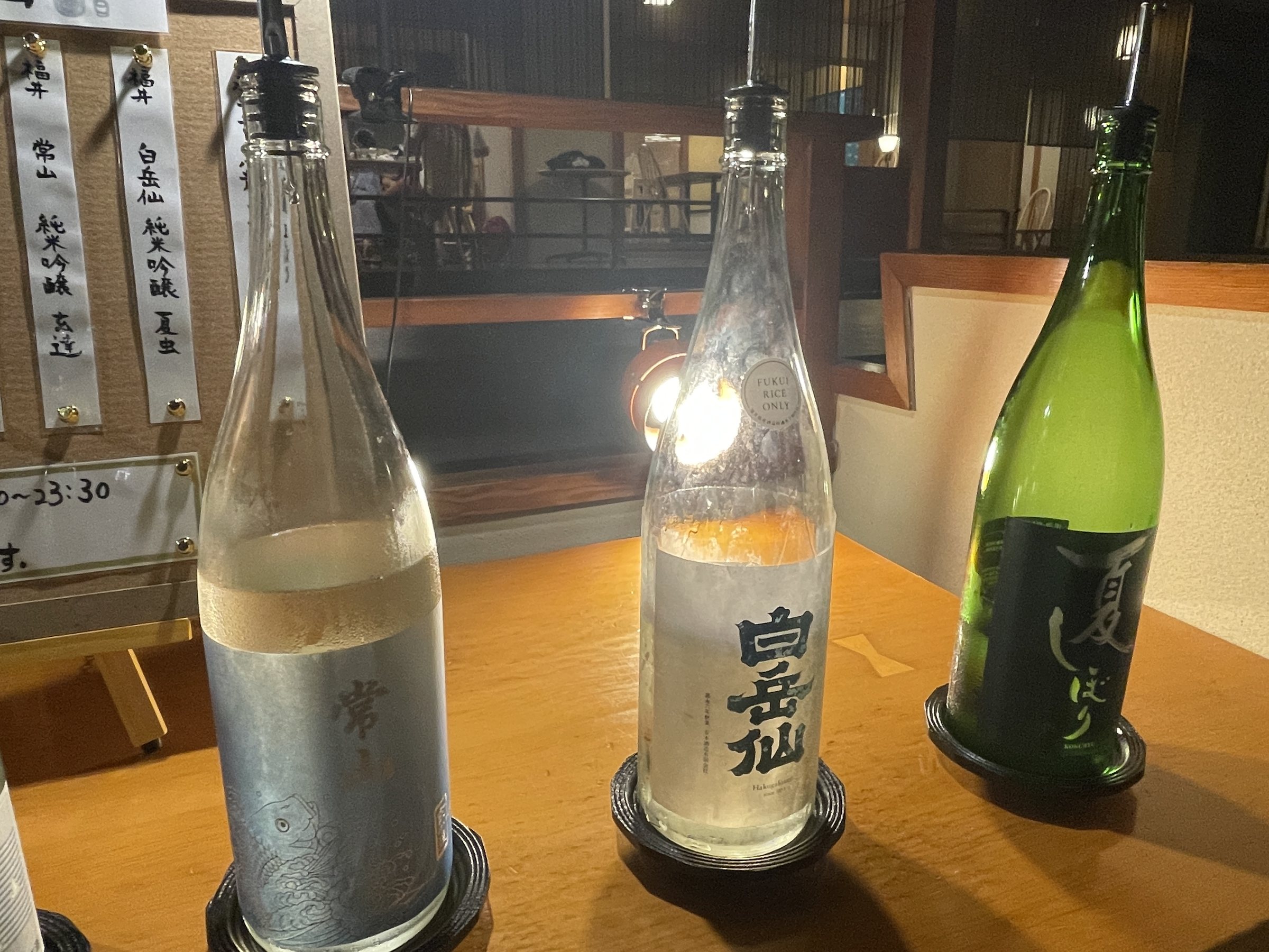 Three bottles of sake, lit from below.