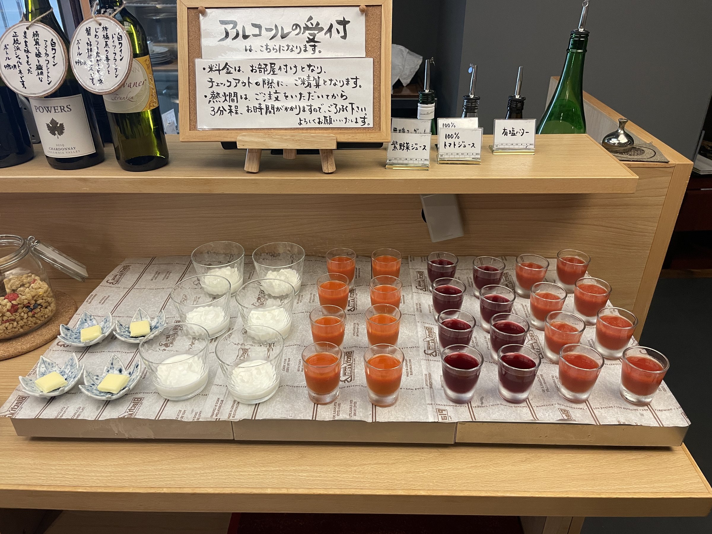 Glasses of juice and yogurt laid out beside a sign for the morning's alcohol.