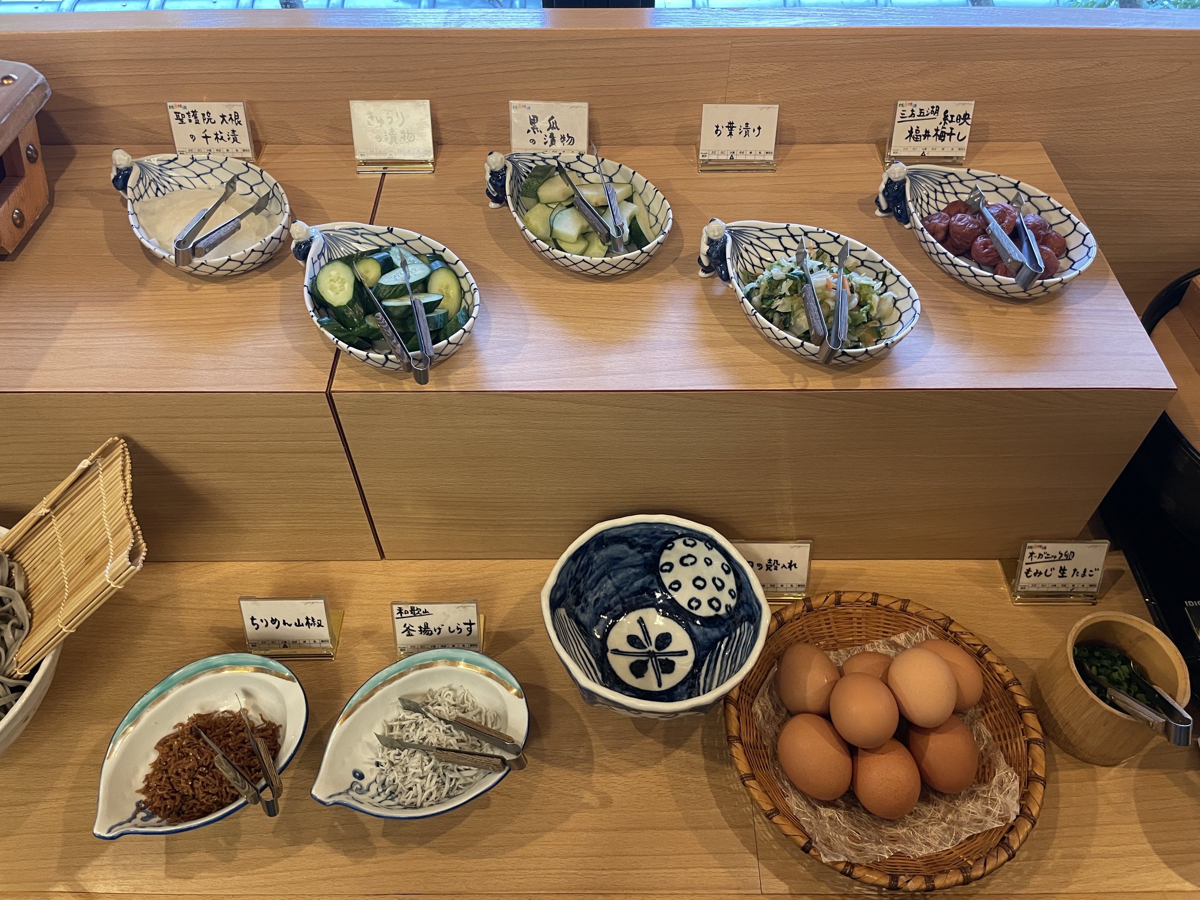 Small bowls of Japanese side dishes and a basket of eggs.
