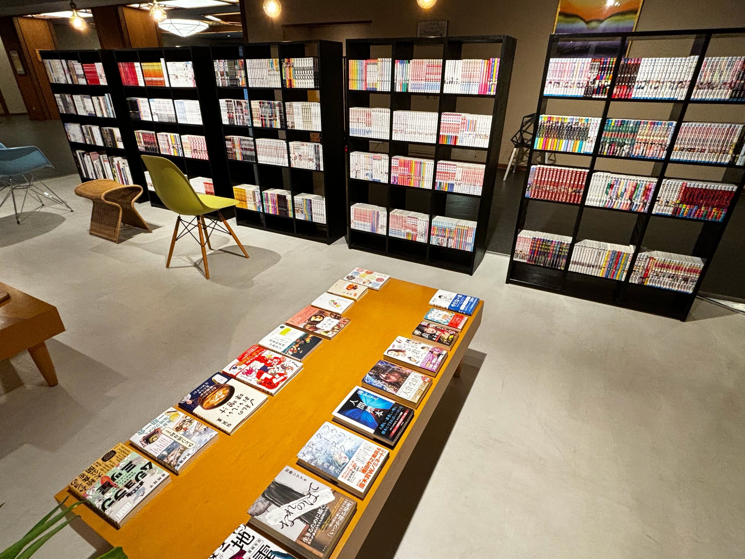 Tall shelves of manga and magazines, with a long table of books laid out face-up.