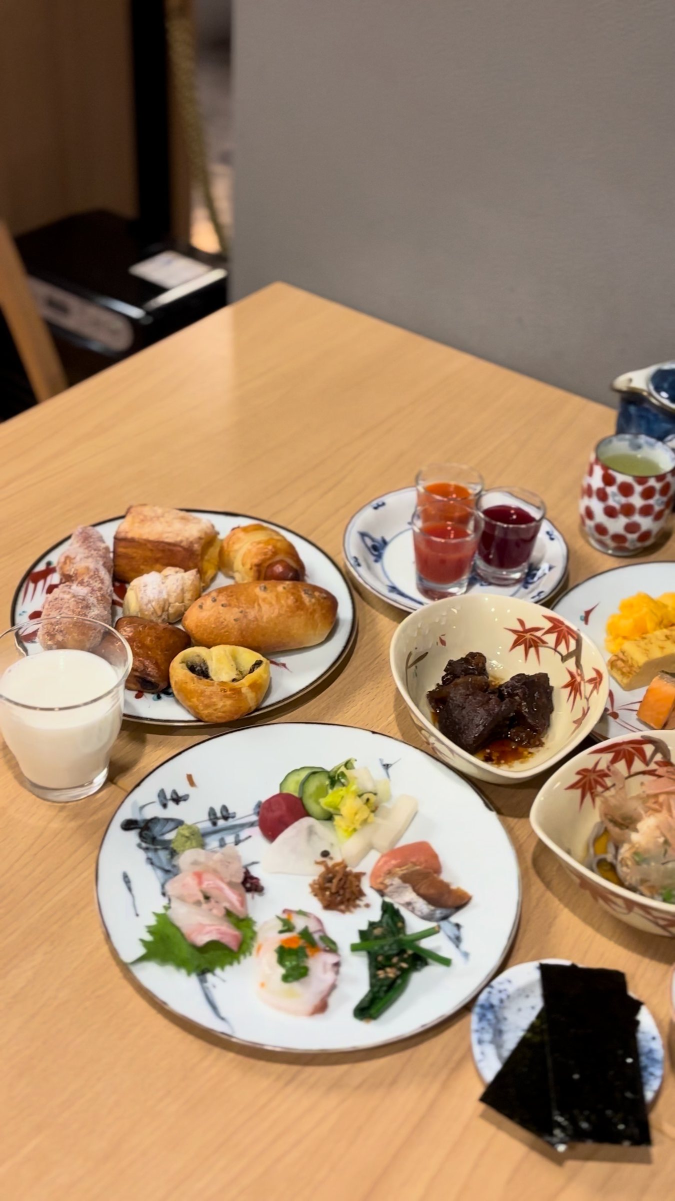 Our breakfast plates: sashimi, breads, a glass of milk and small side dishes.