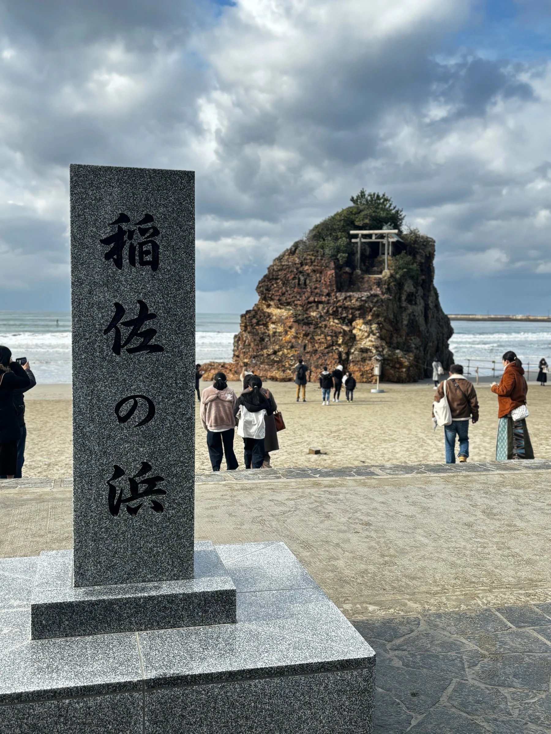 The stone marker of Inasa no Hama, with the rock islet of Benten-jima behind.