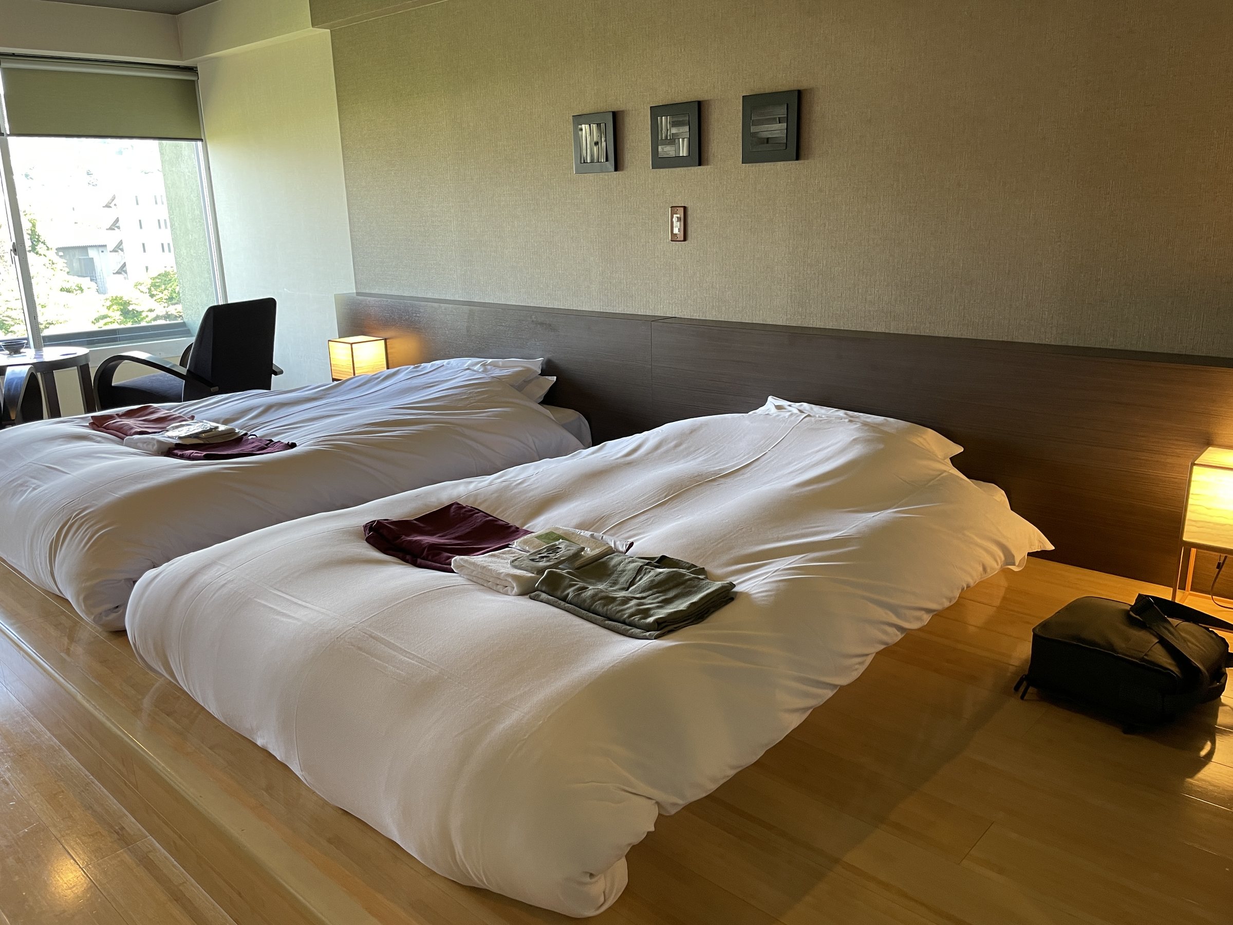 Our room: low twin beds on pale wooden flooring, with a window onto the town.