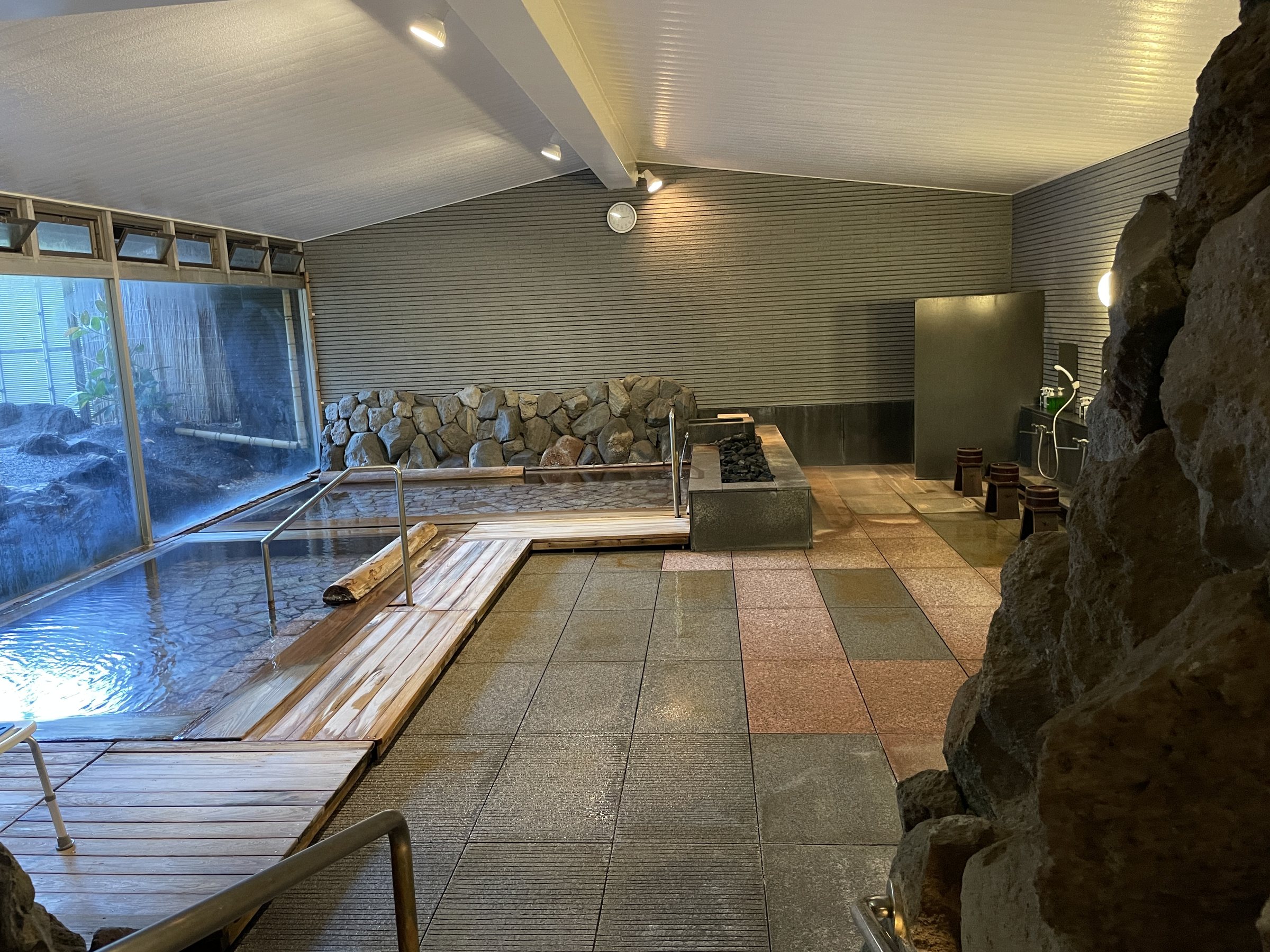 The large indoor bath, with timber edging and stone walls beyond the glass.
