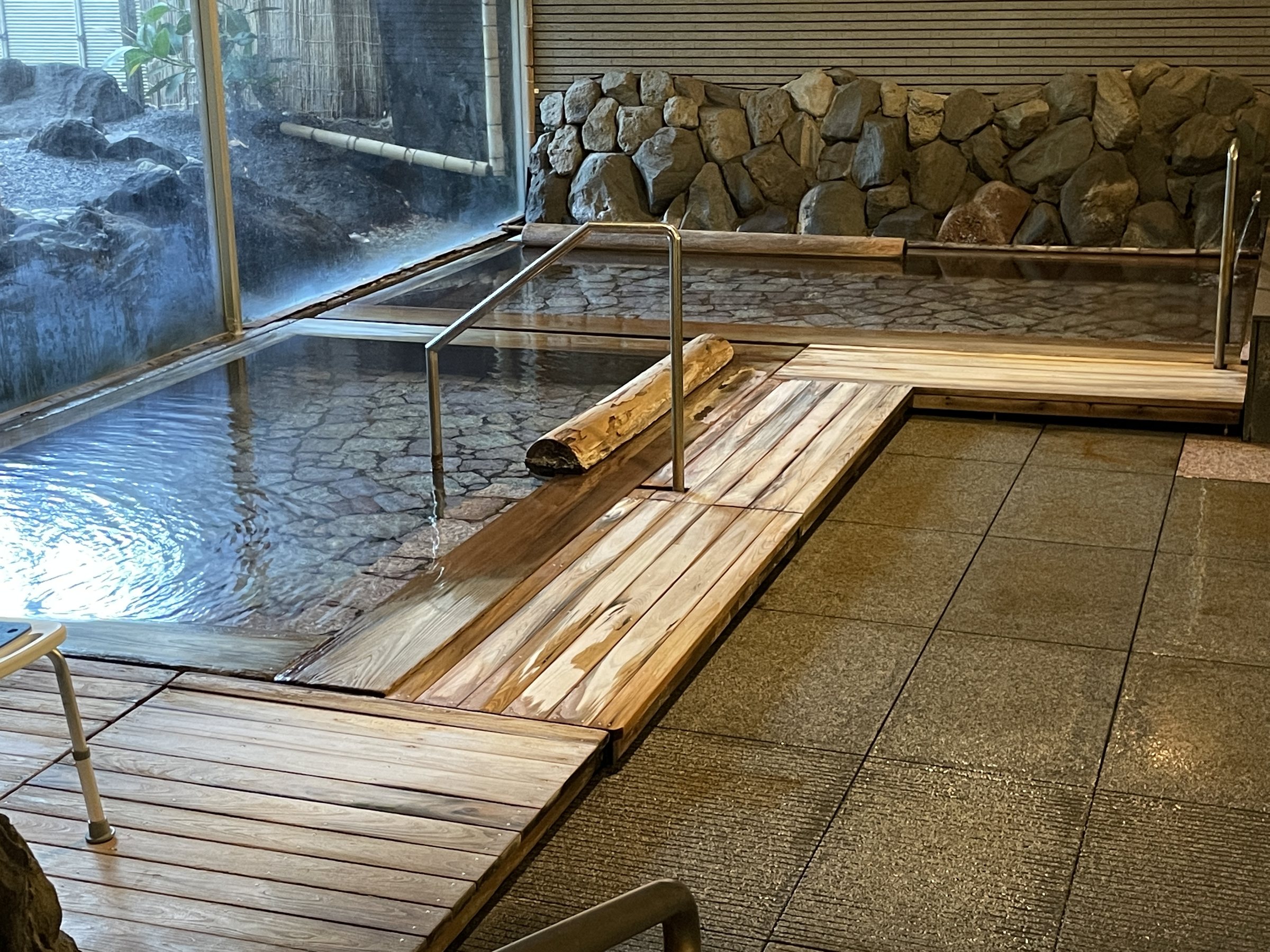 The indoor bath: clear water over a stone floor, with a timber walkway.