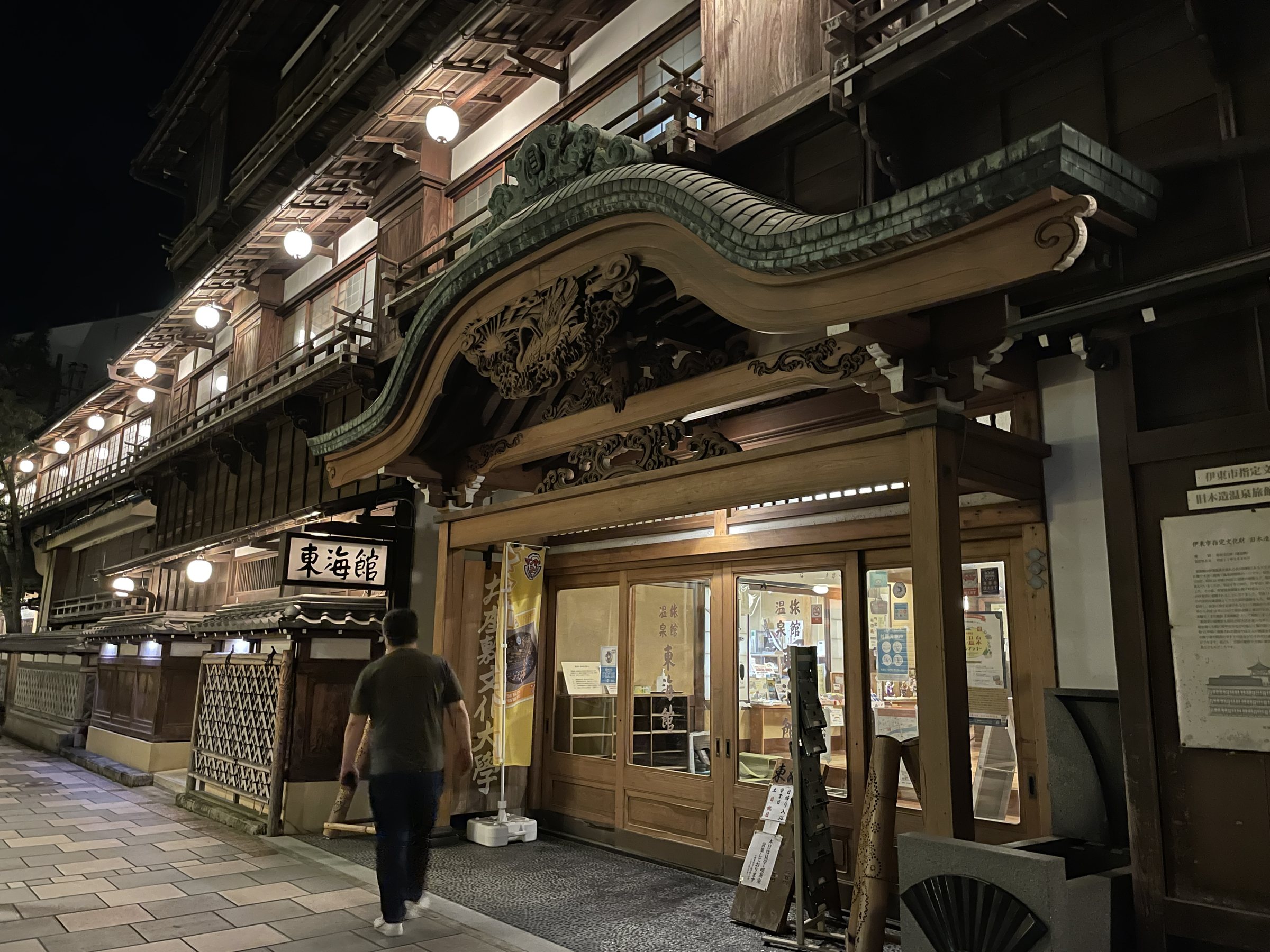 Tokaikan at night: a multi-story wooden building with an ornate gabled entrance, lit up along the street.