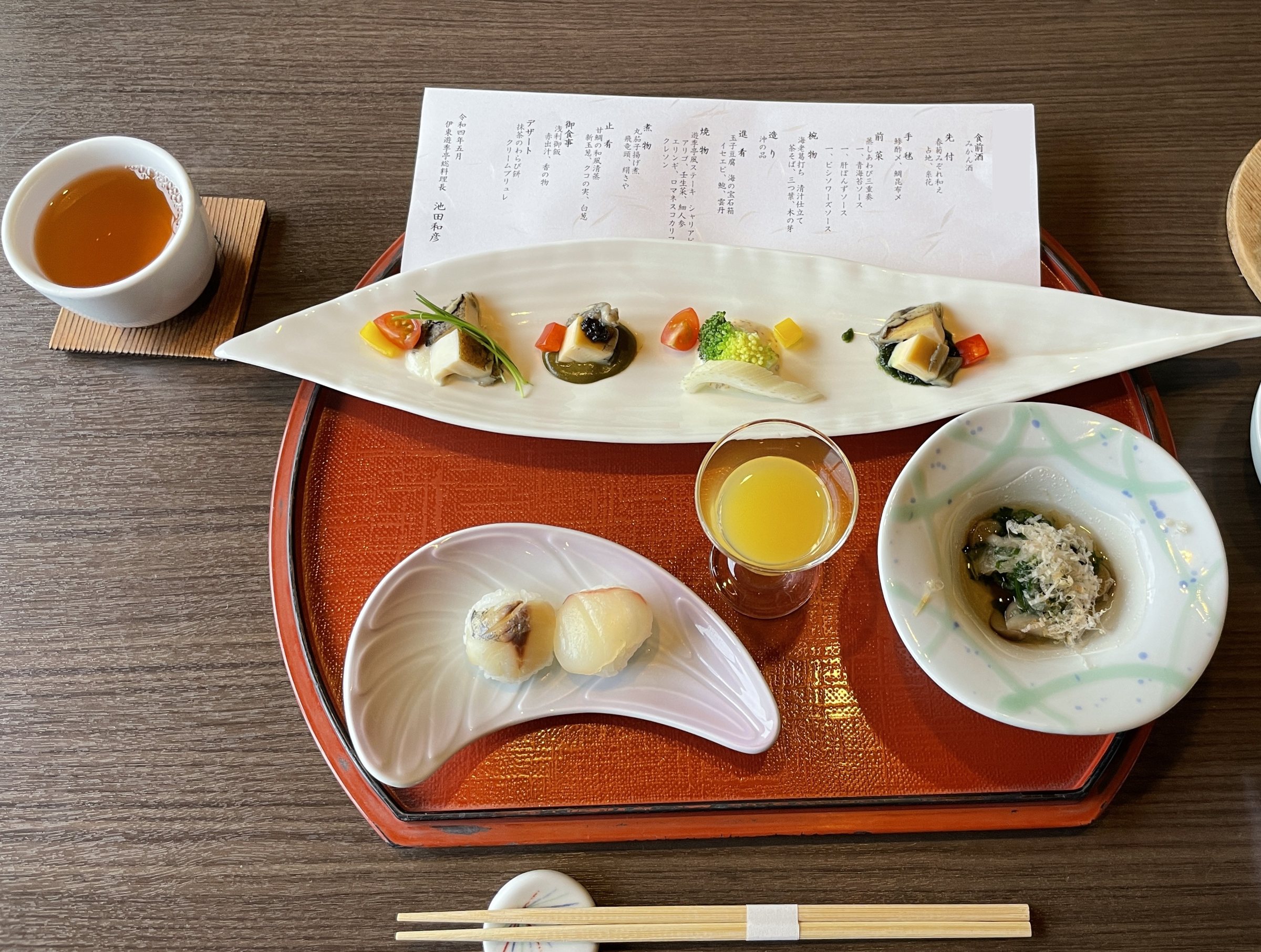 The opening course: a long plate of small bites, with a mini temari sushi and a dish of greens.