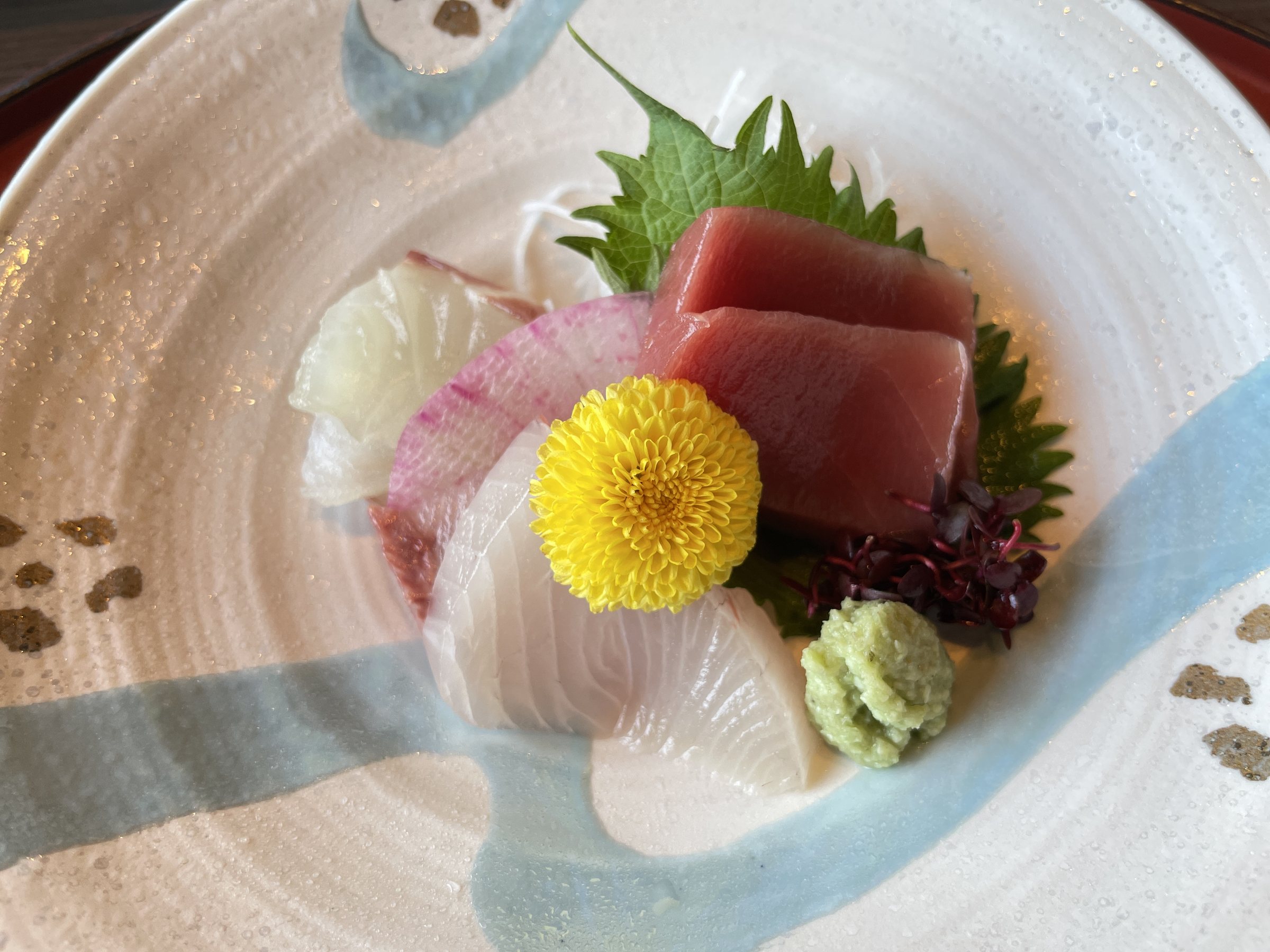Sashimi with tuna, white fish, a yellow chrysanthemum and fresh wasabi.