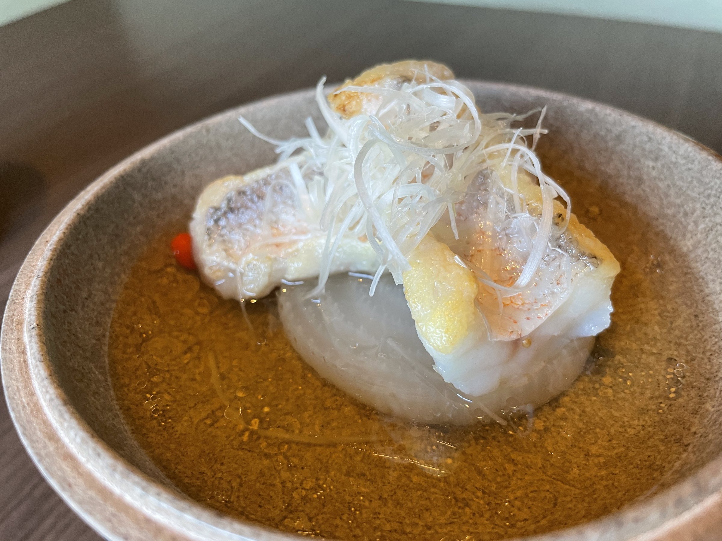 Tilefish on daikon in broth, topped with fine shreds of white leek.