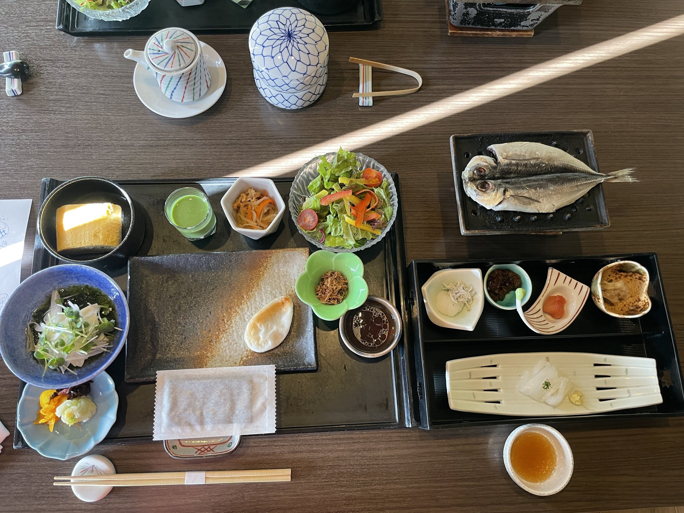 Breakfast from above: small side dishes, salad and a grilled dried fish.
