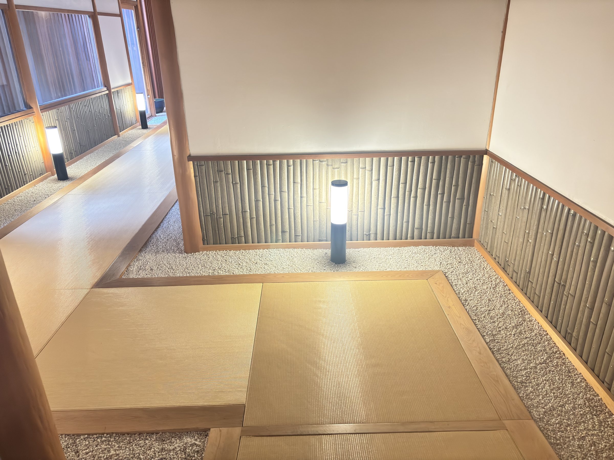 A tatami walkway lined with white gravel and a lantern.