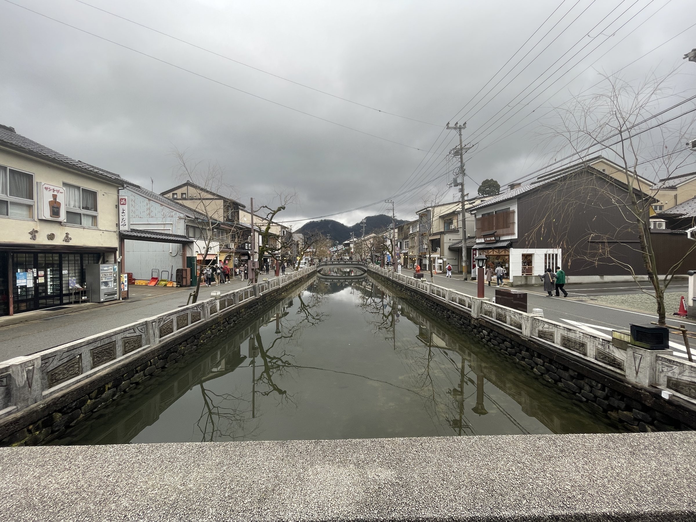 Kinosaki’s willow-lined canal under a gray winter sky.