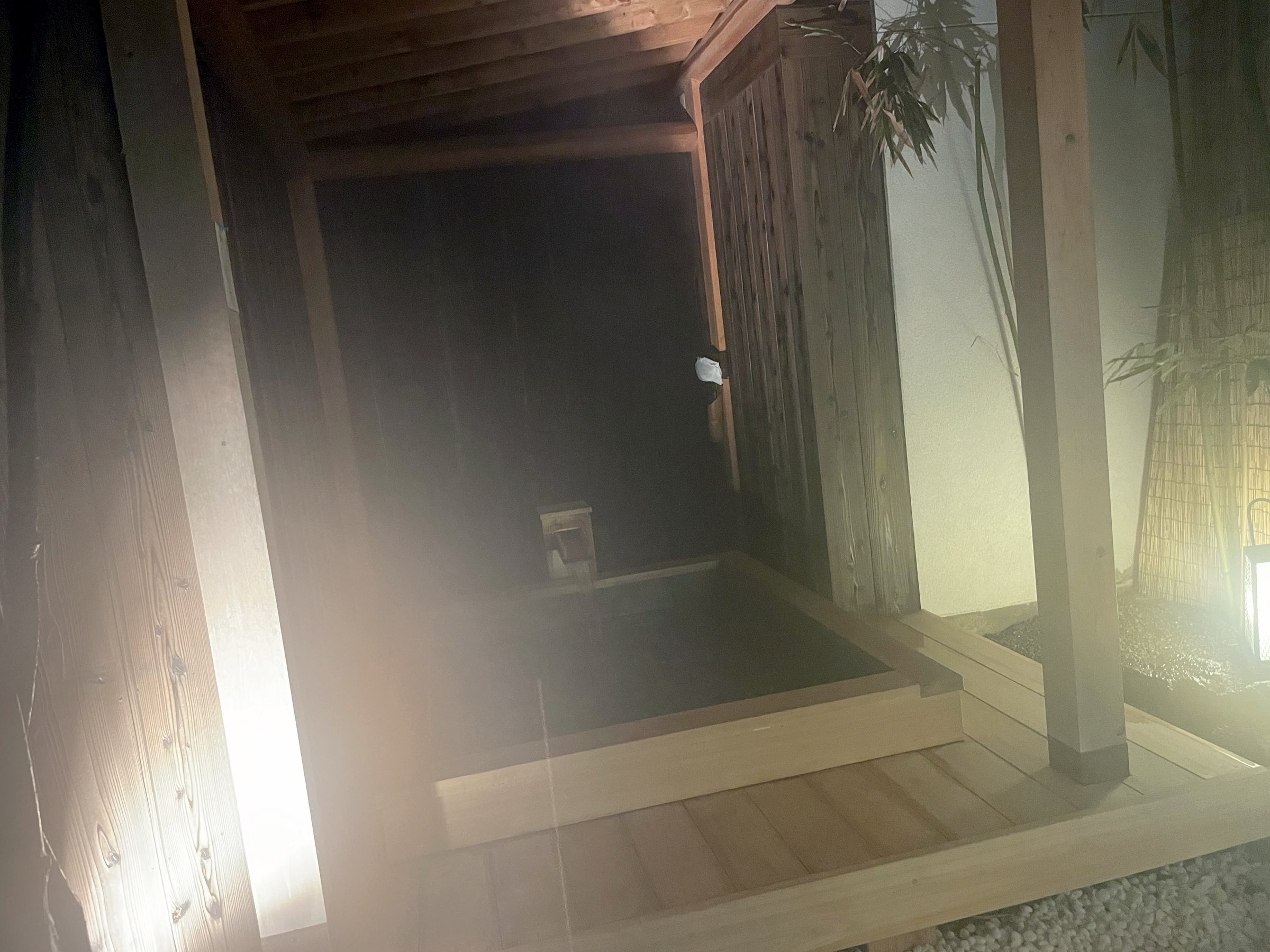 The outdoor bath at night, in a wooden enclosure.