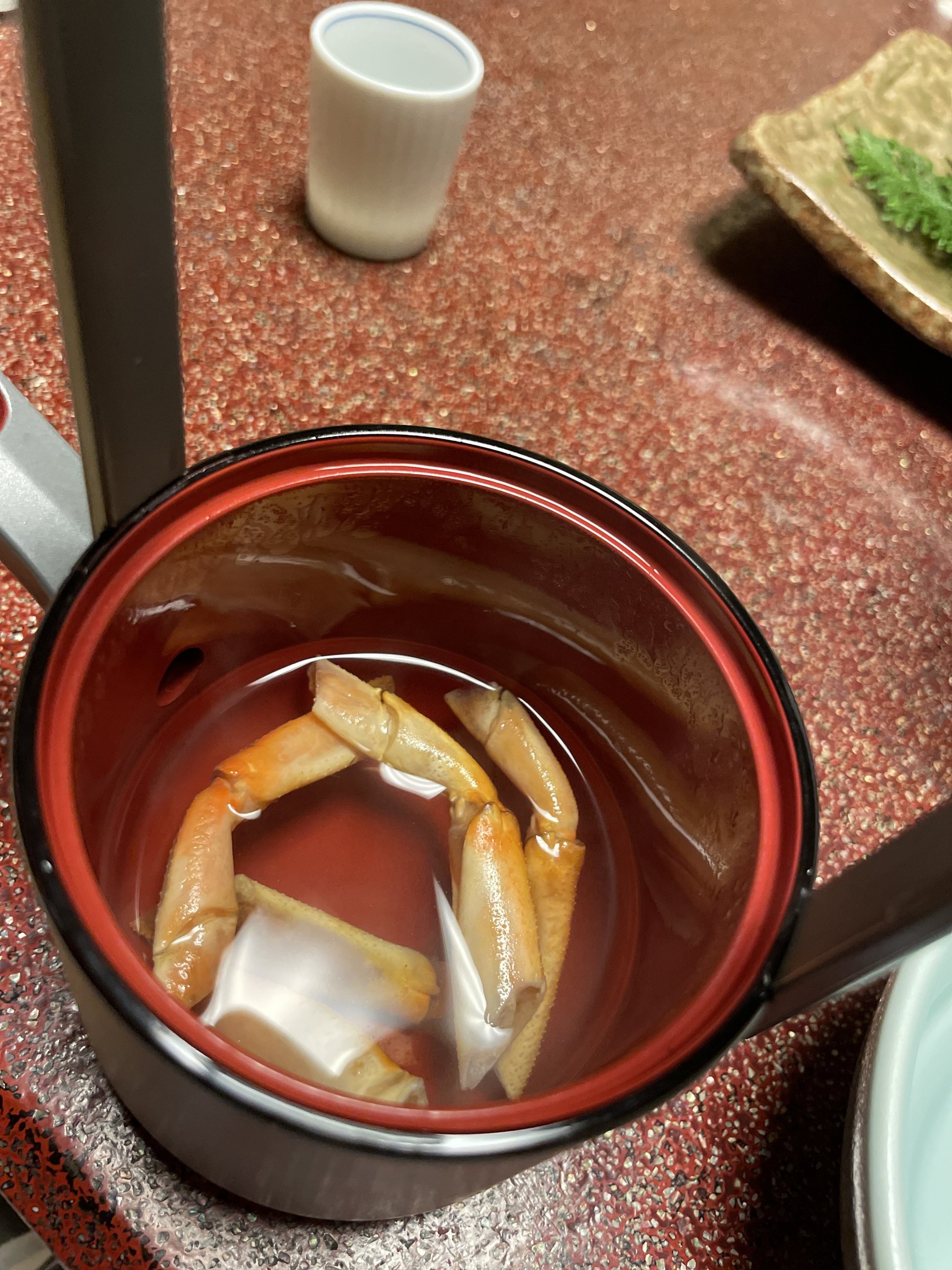 A crab leg in a lacquered cup.