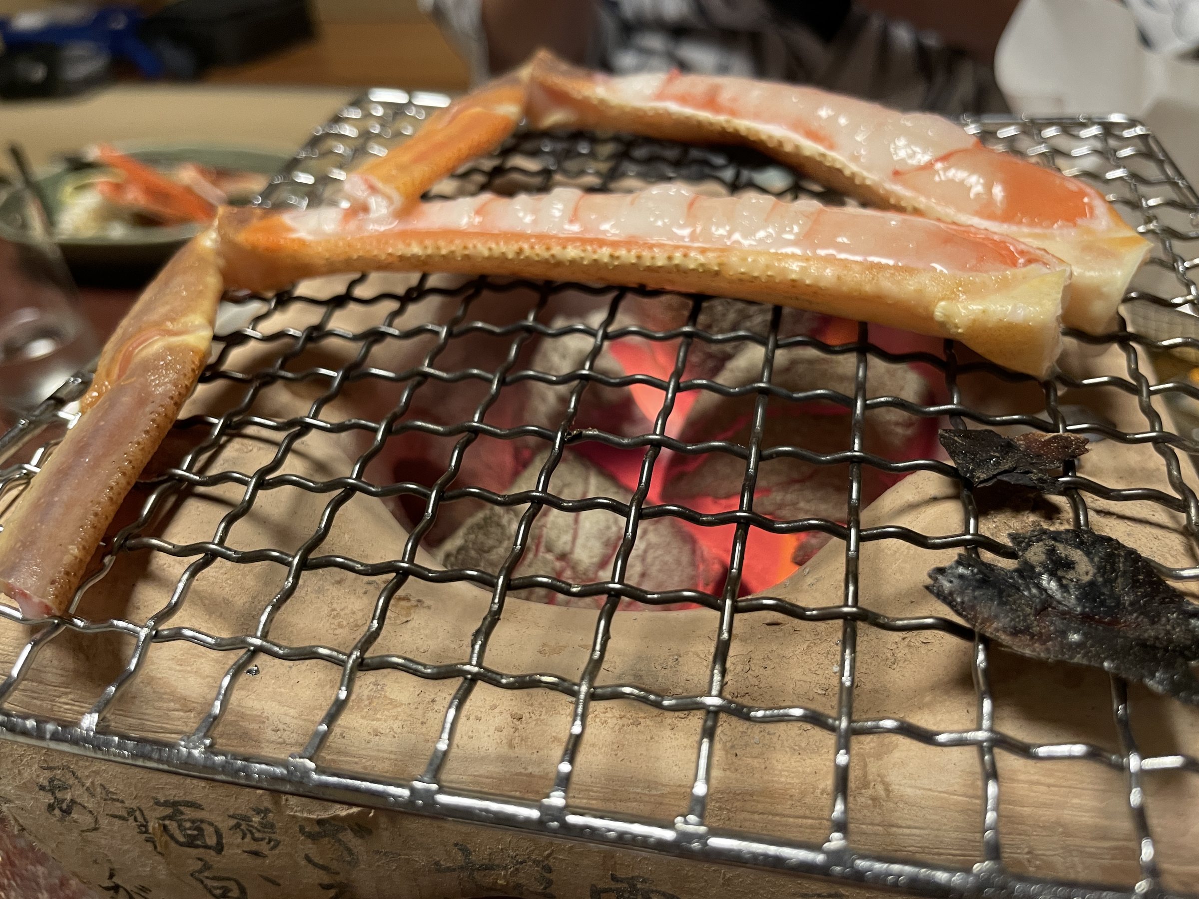Crab legs grilling over charcoal.