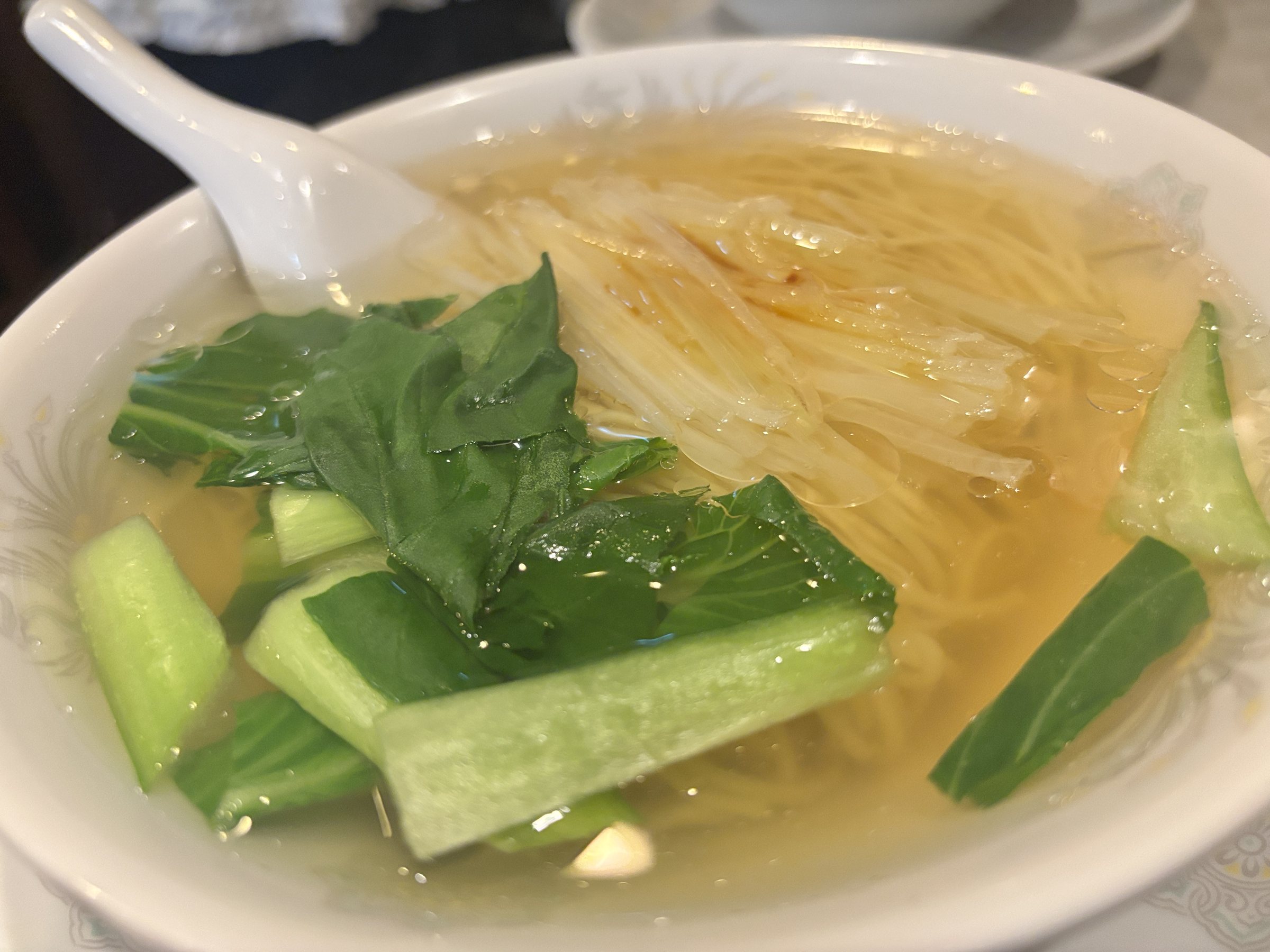 Noodles in clear broth with greens and shredded spring onion.