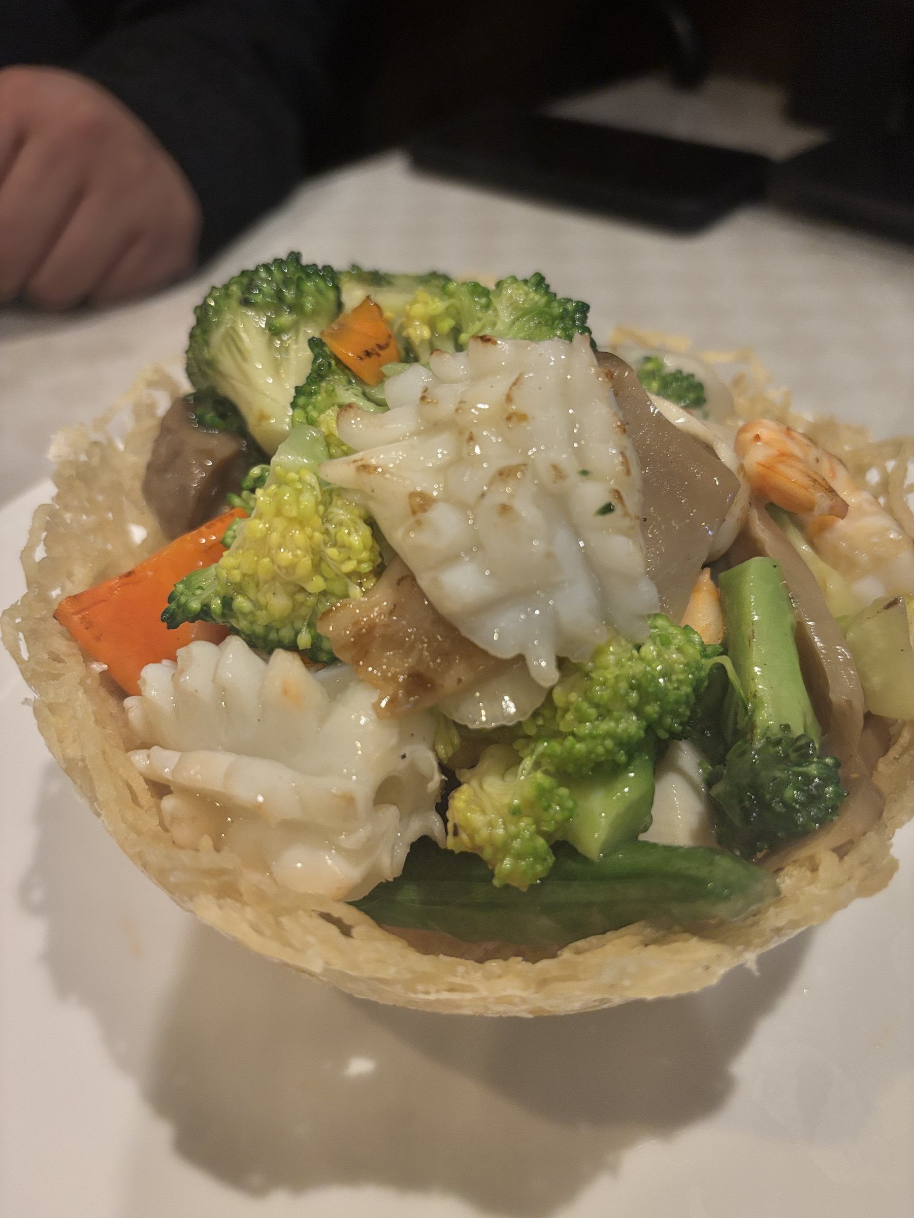 A stir-fry of squid, broccoli and vegetables in a crisp noodle basket.