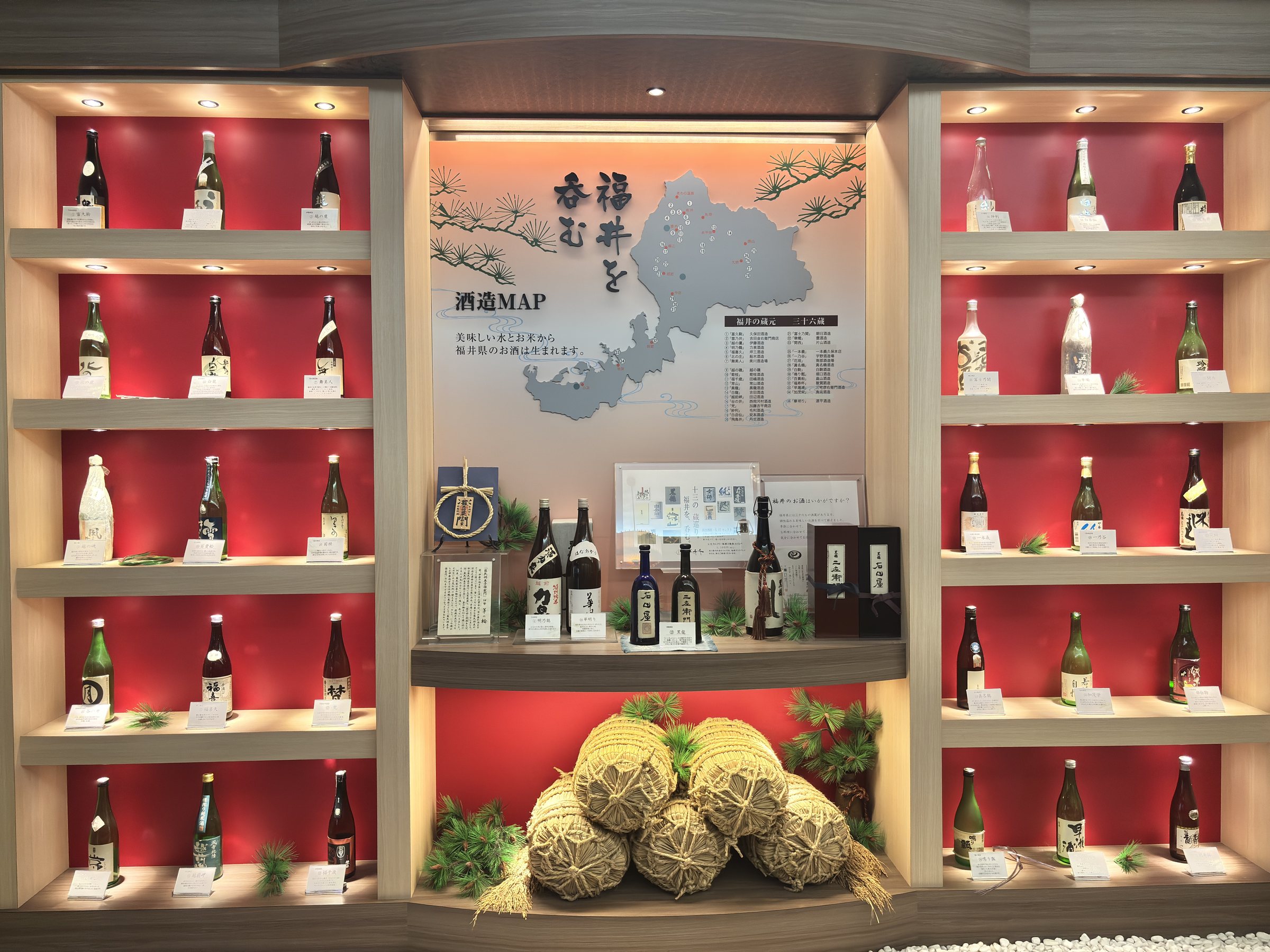 A wall of Fukui sake bottles beside a map of the prefecture.