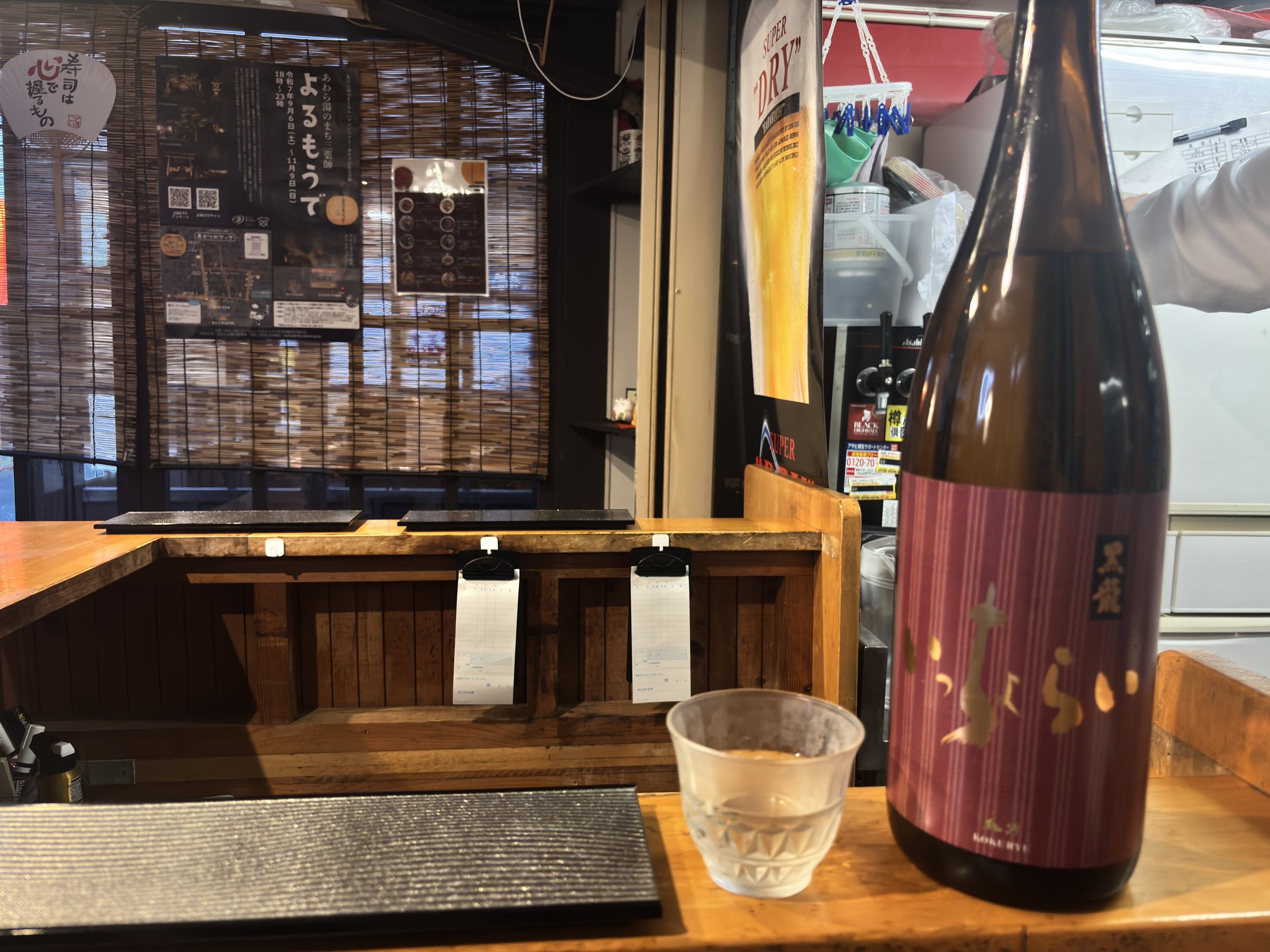 A bottle of sake and a glass at the counter.