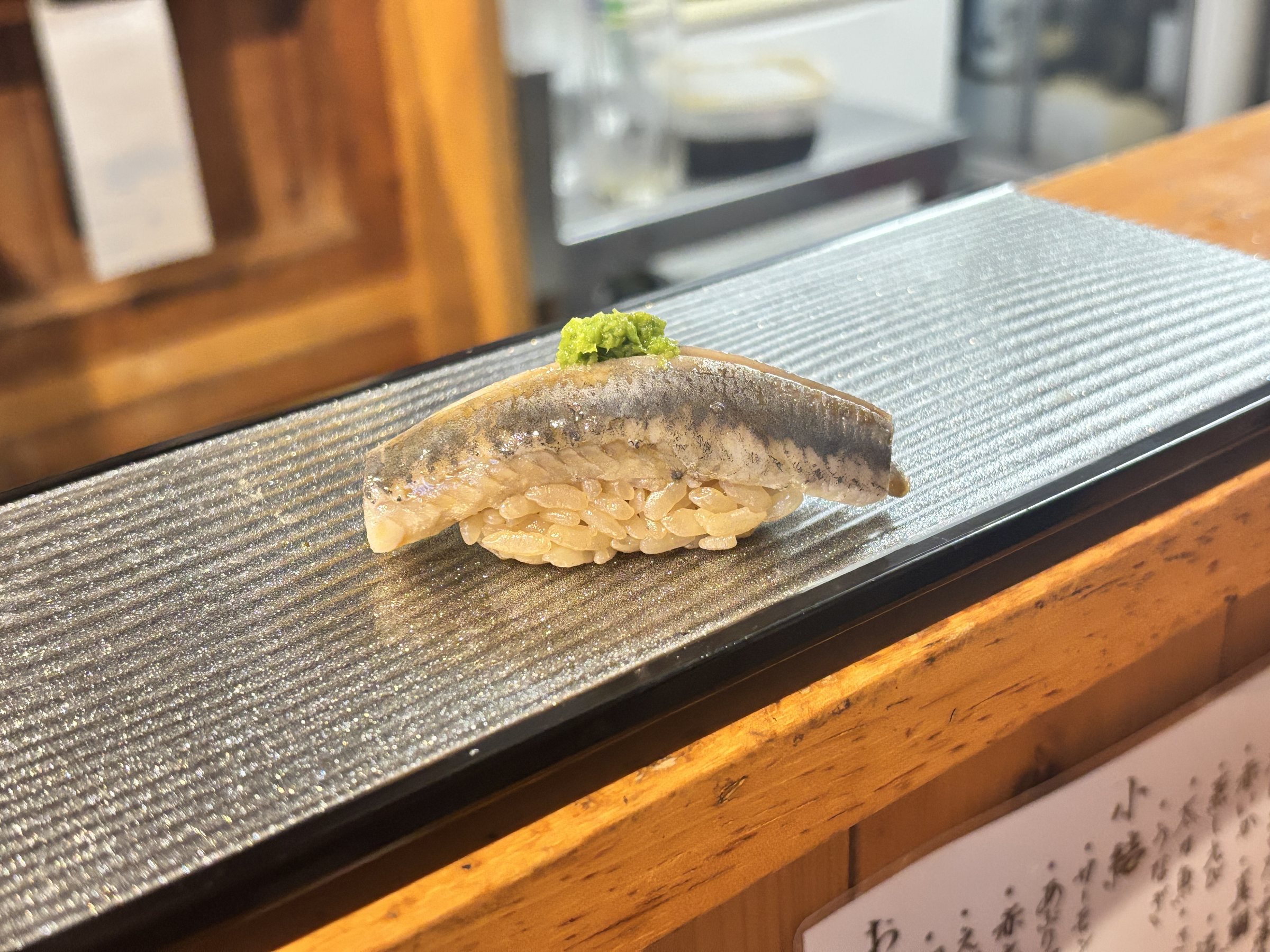 A nigiri of silver-skinned fish topped with grated ginger.