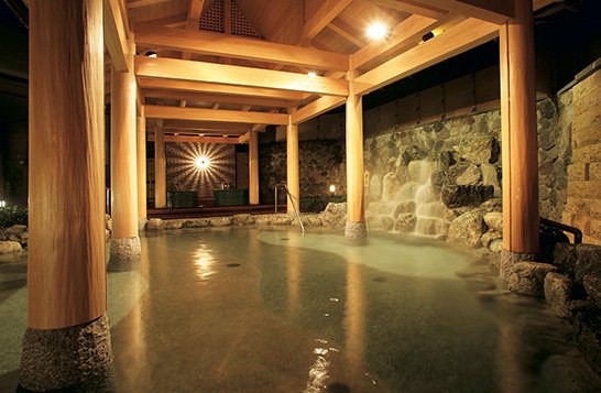 An outdoor bath under a timber roof at night (photo from the ryokan’s official website).