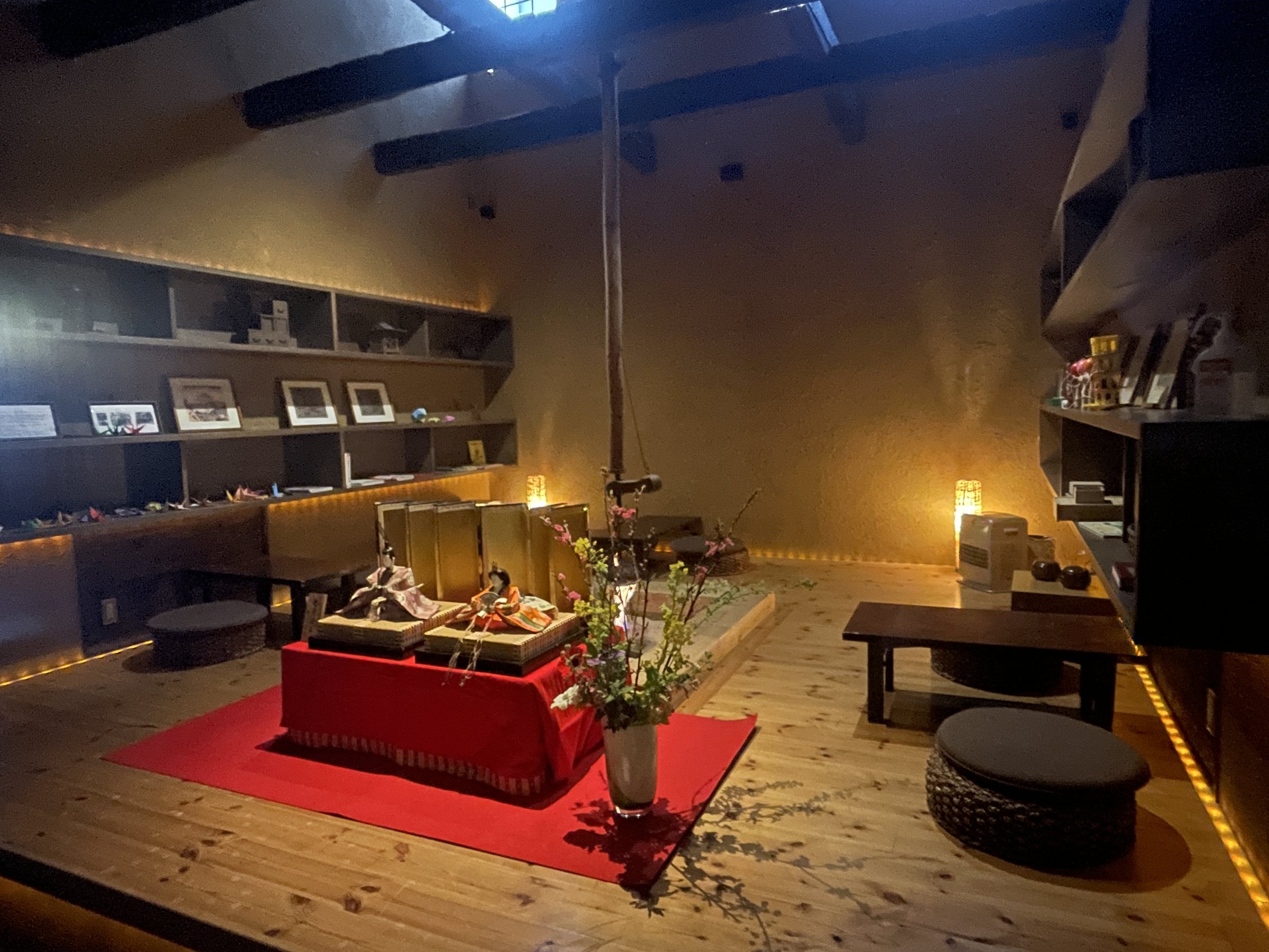 The reading room, with old-fashioned toys displayed on a red cloth and low seats around them.